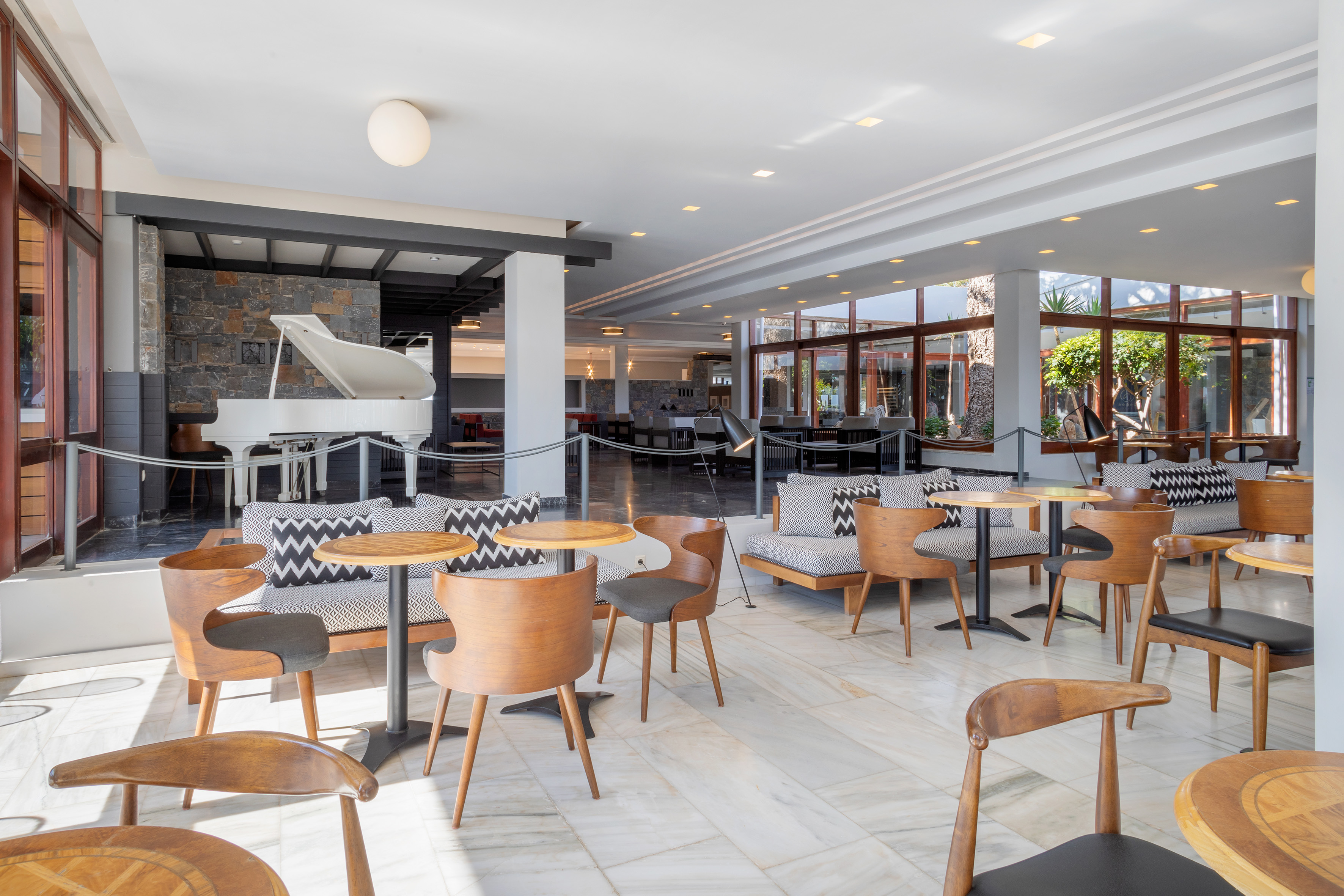 Hotel lounge with white grand piano, modern wood furniture, and patterned seating.