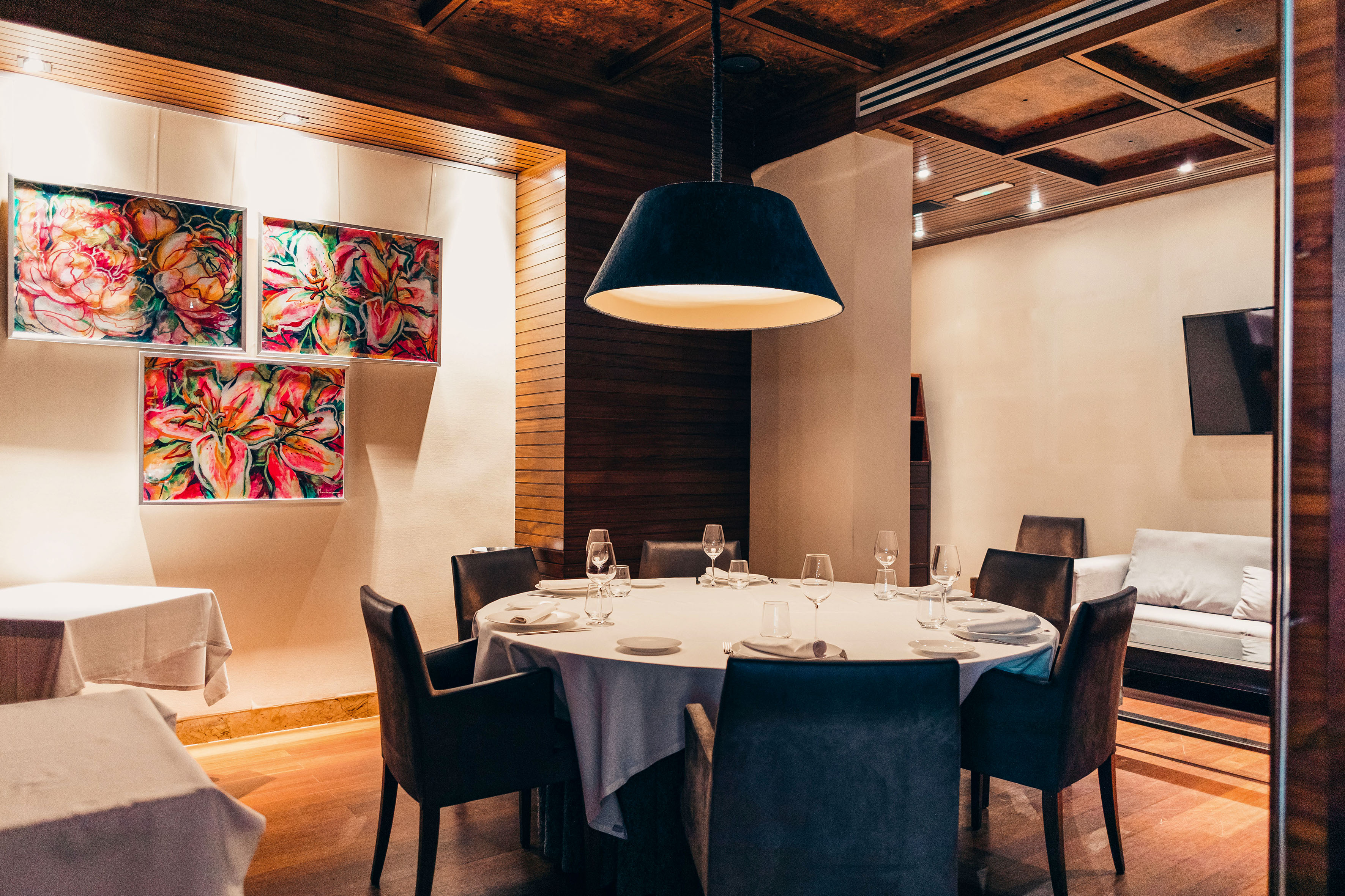 Elegant restaurant dining area with round table, floral art, and modern lighting.