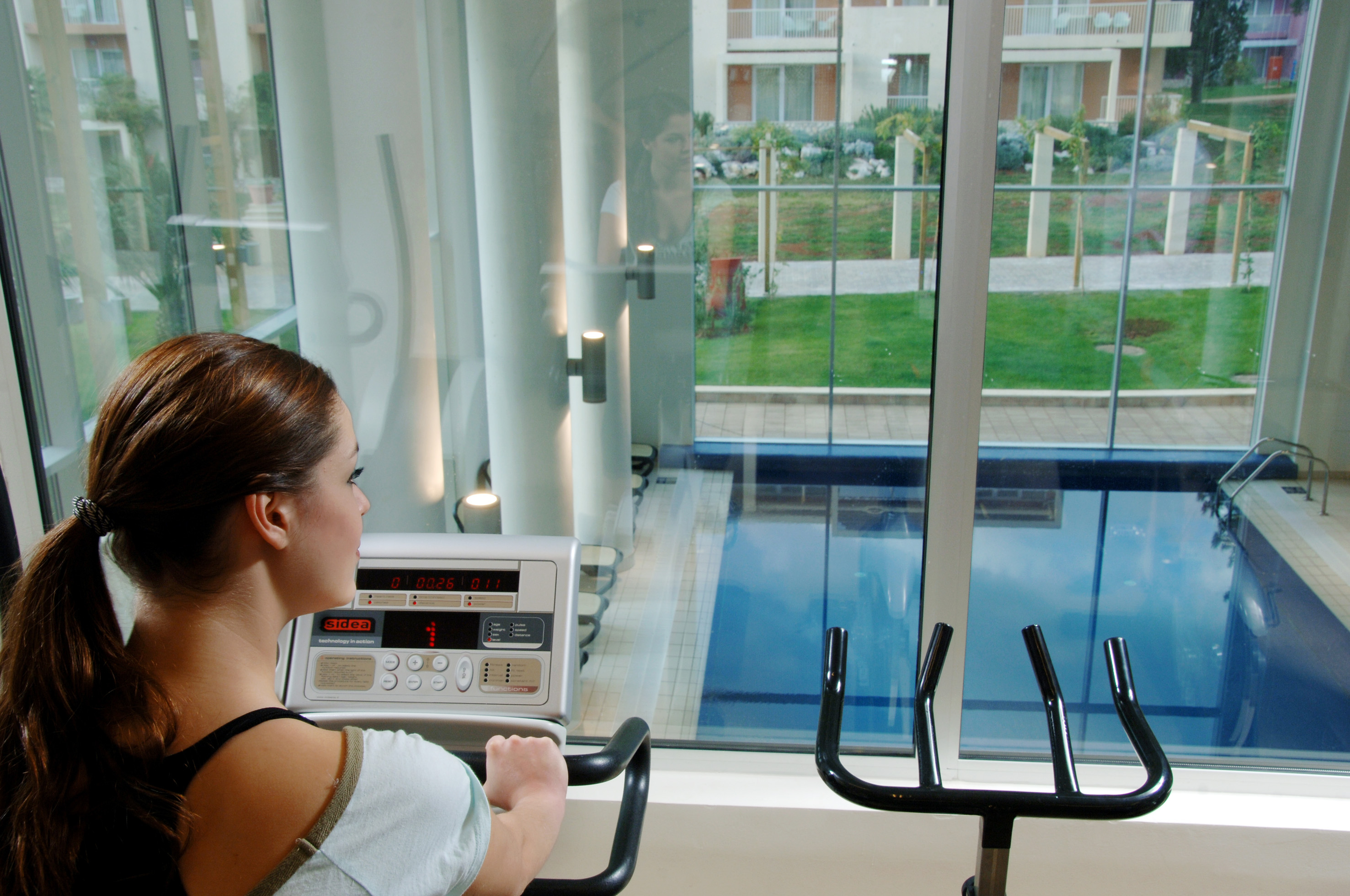 a woman on a treadmill looking at a pool