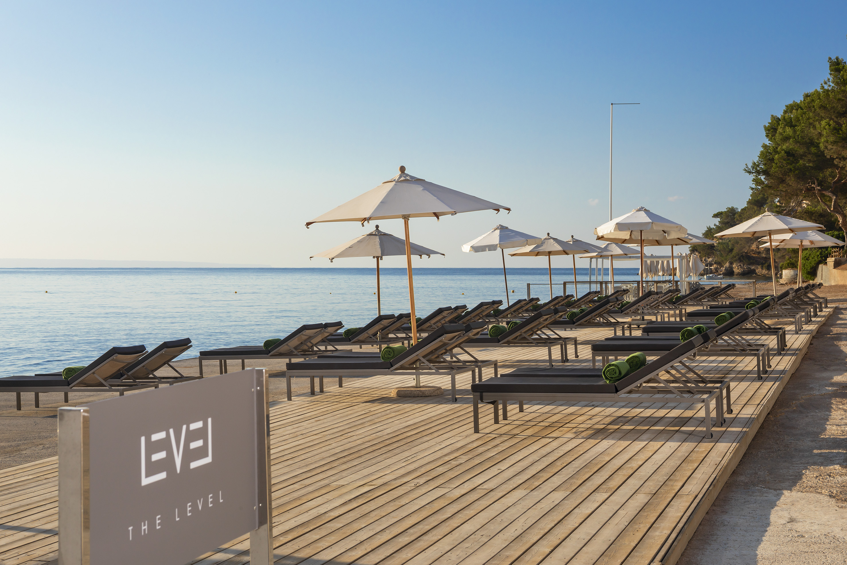 EVE THE LEVEL resort beach, sun loungers, umbrellas, wooden deck, calm sea.