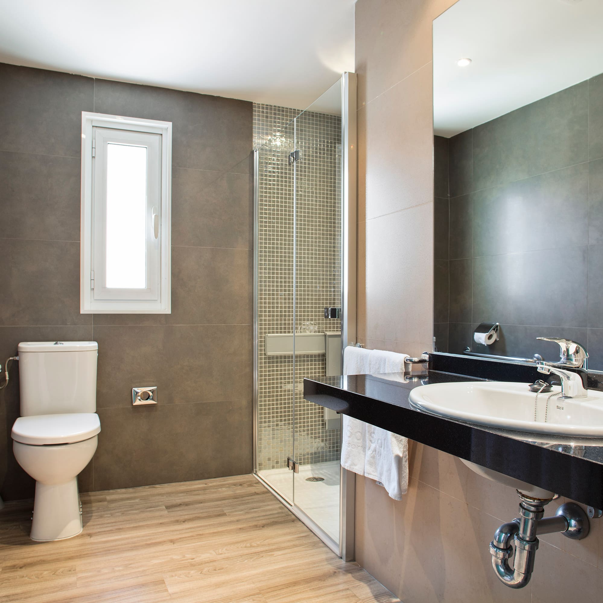 Contemporary bathroom with toilet, shower, sink vanity, grey walls, wood floor.