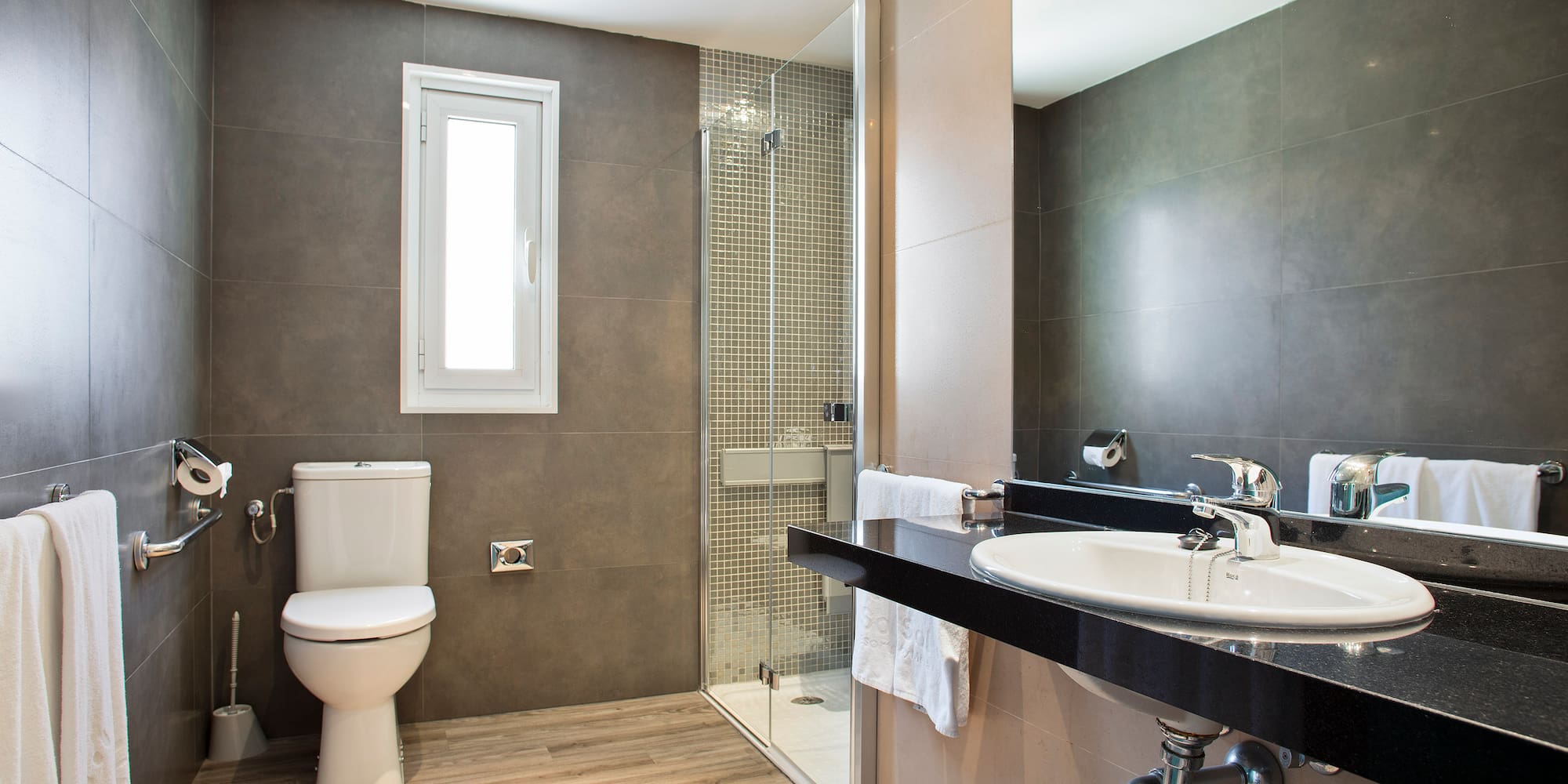 Contemporary bathroom with toilet, shower, sink vanity, grey walls, wood floor.