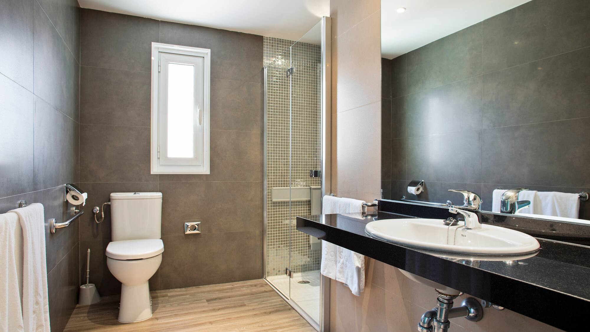 Contemporary bathroom with toilet, shower, sink vanity, grey walls, wood floor.