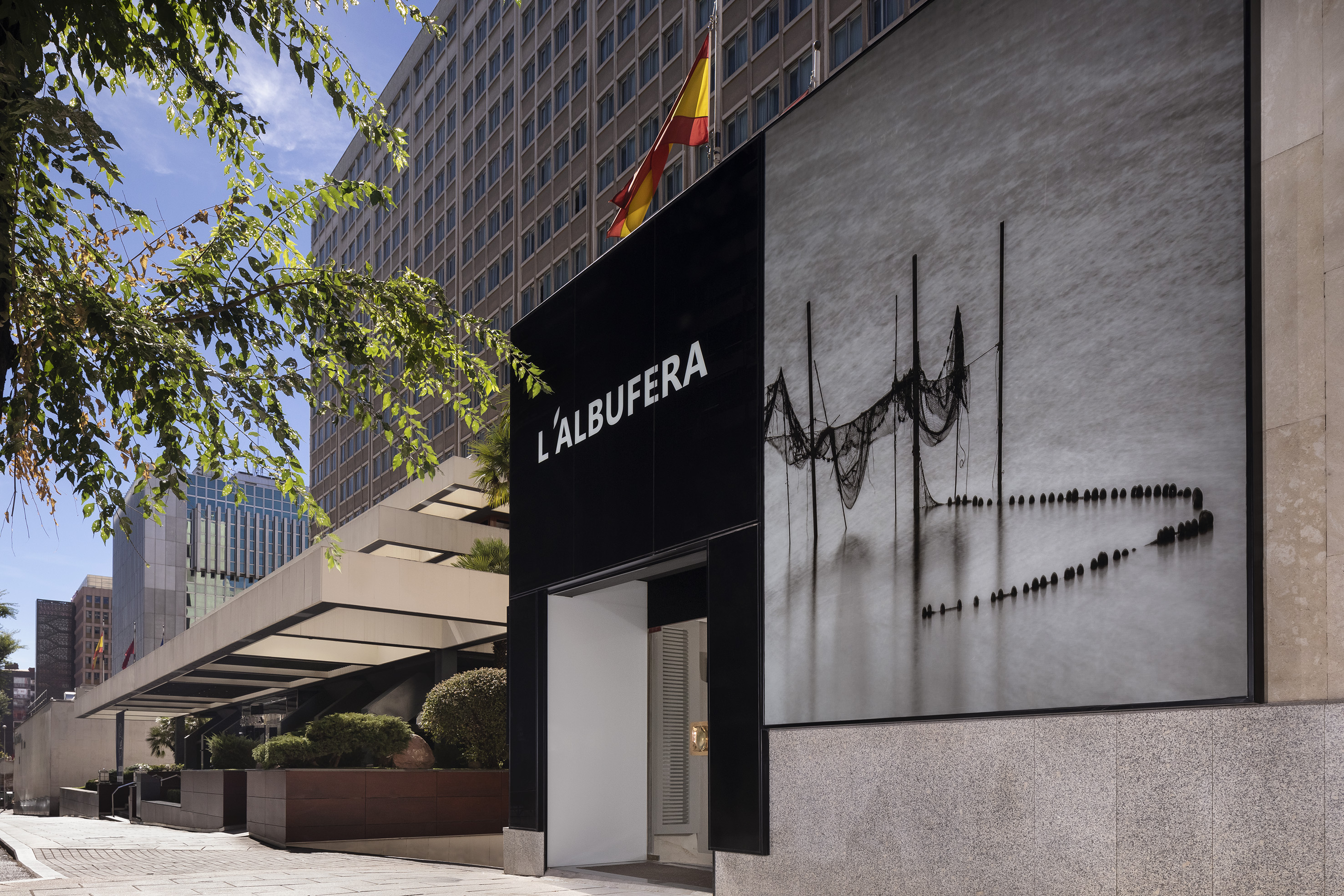 L'ALBUFERA hotel facade with fishing net art, Spanish flag, modern design.