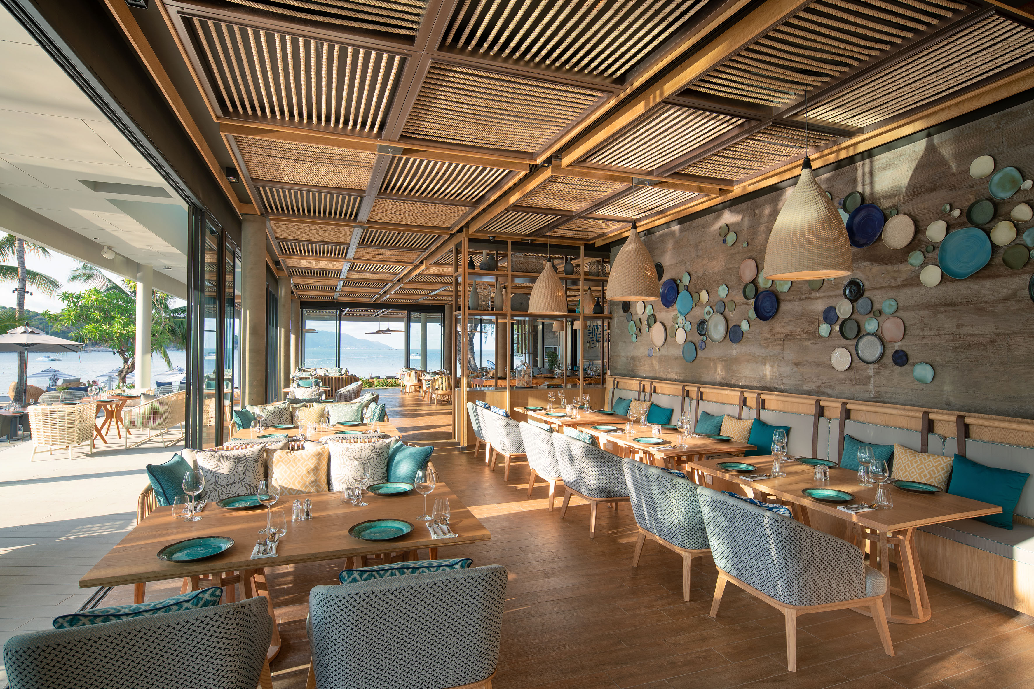 Luxury restaurant with ocean view, modern wooden decor, and teal accents.