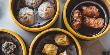 a group of dim sum in yellow containers