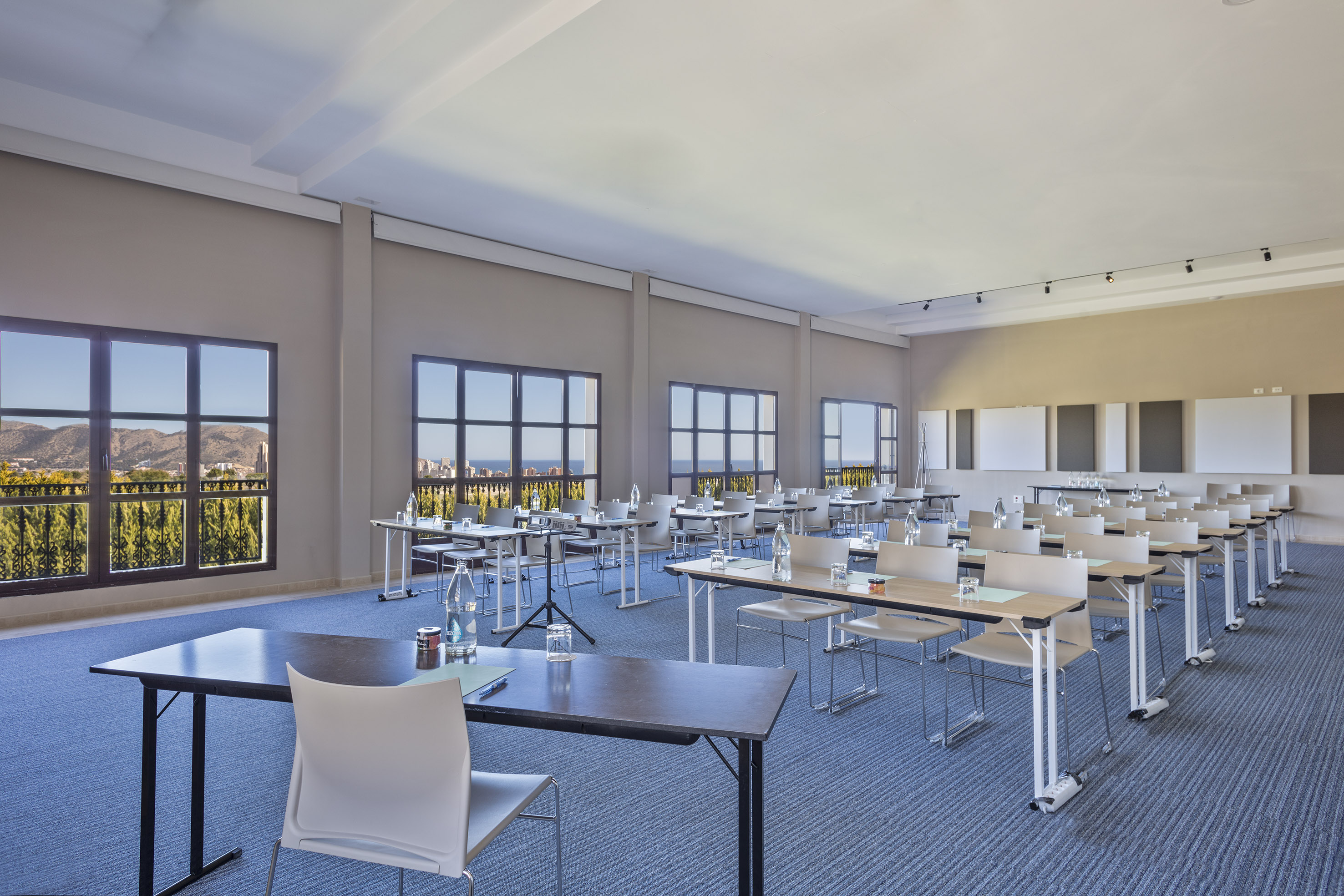 Bright conference room, classroom setup, large windows, coastal view.