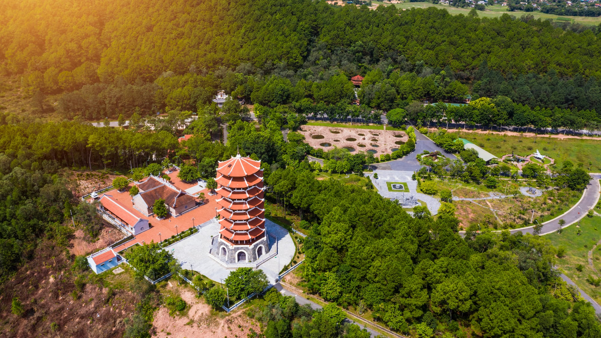 a tower with a red and white building surrounded by trees