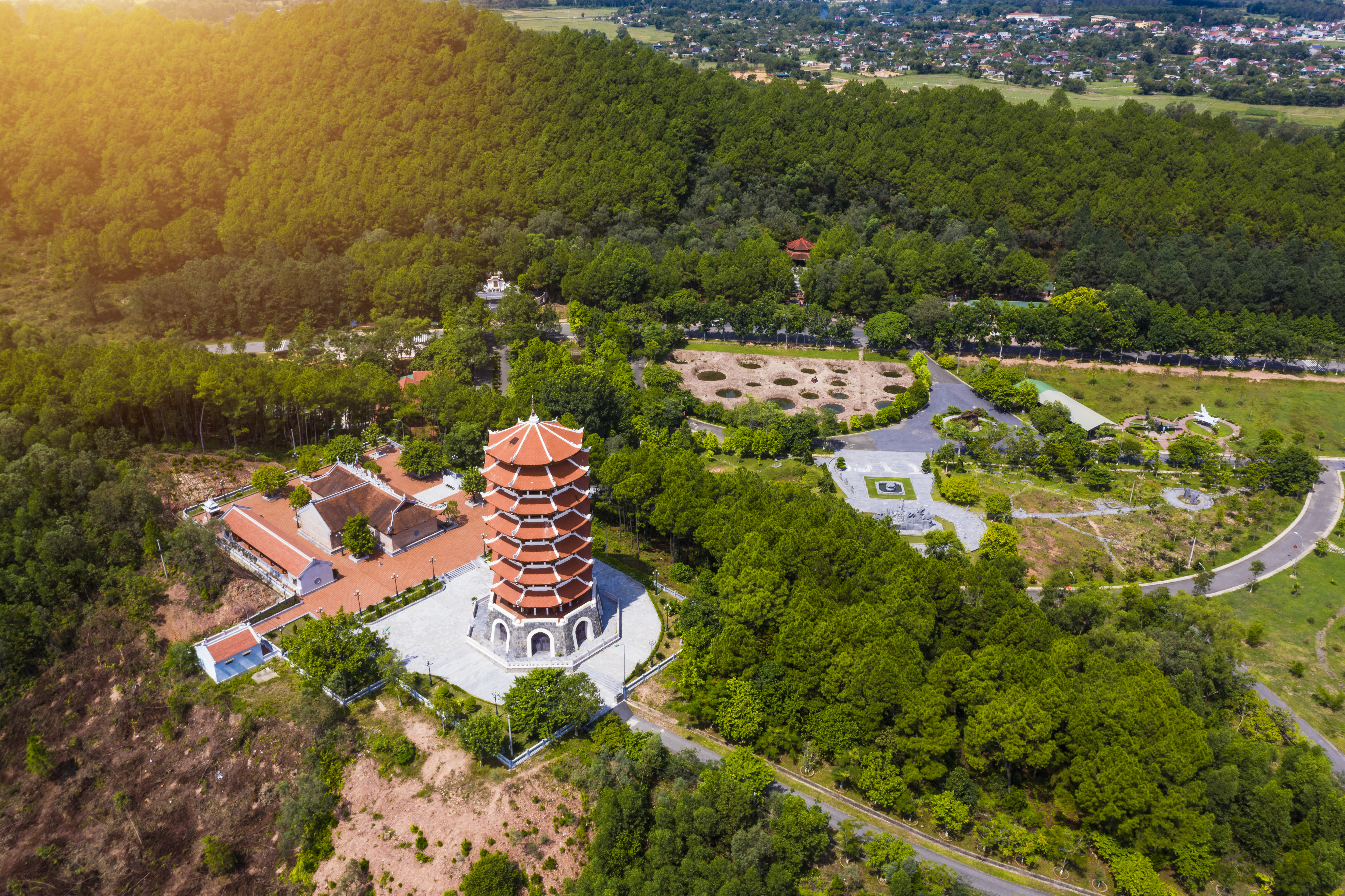 a tower with a red and white building surrounded by trees