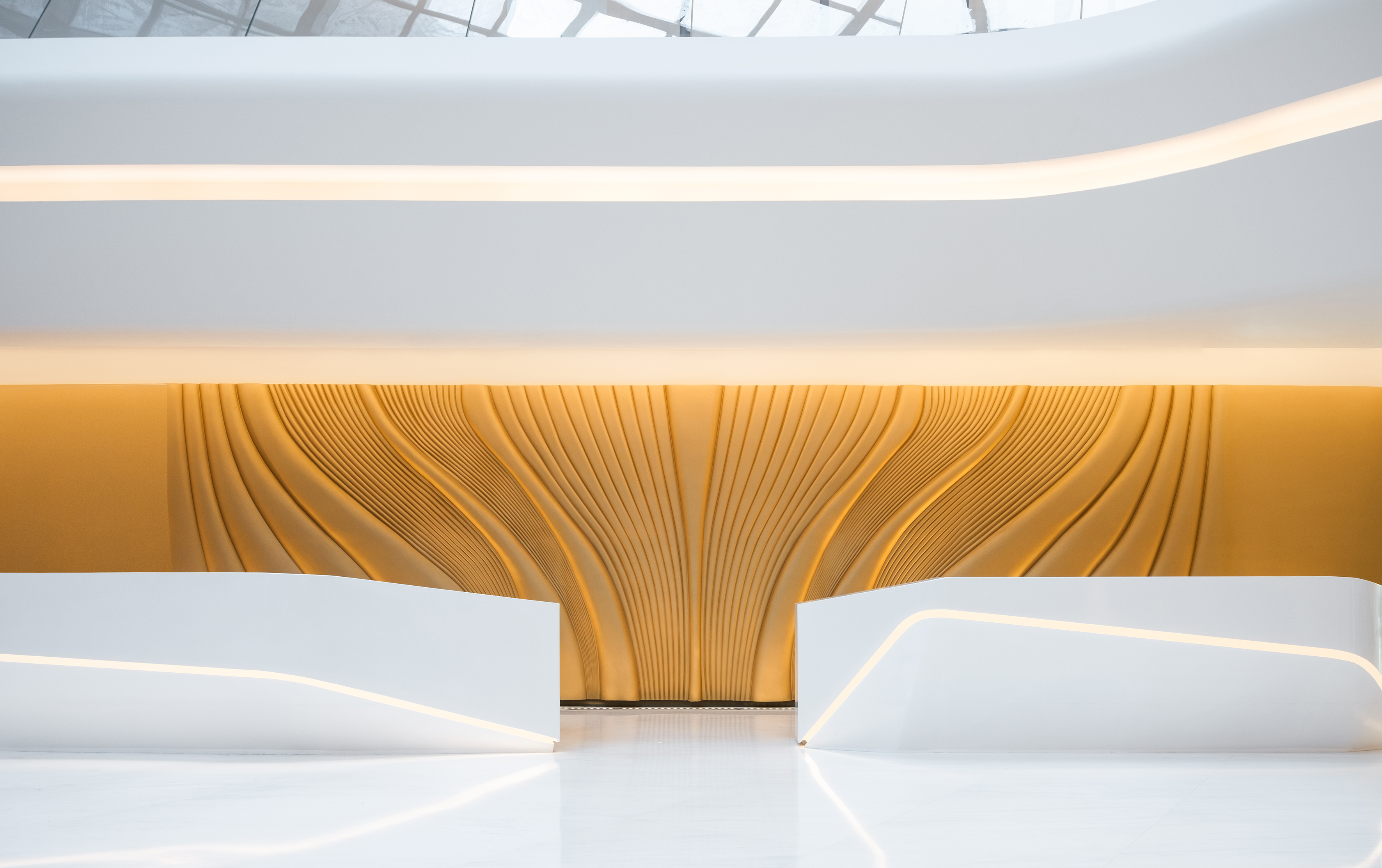 Contemporary reception lobby with white desks and backlit golden textured wall.