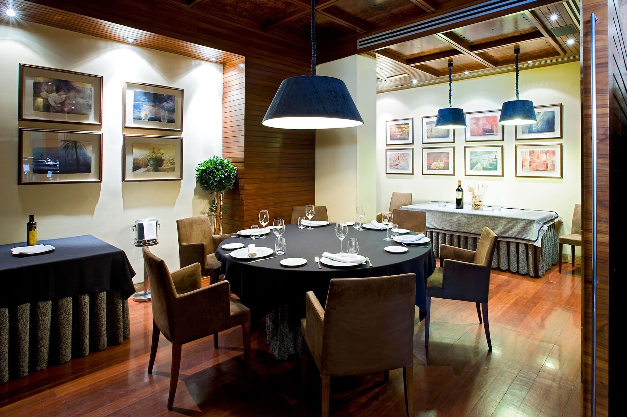 Restaurant dining room with round table, brown chairs, and framed art.