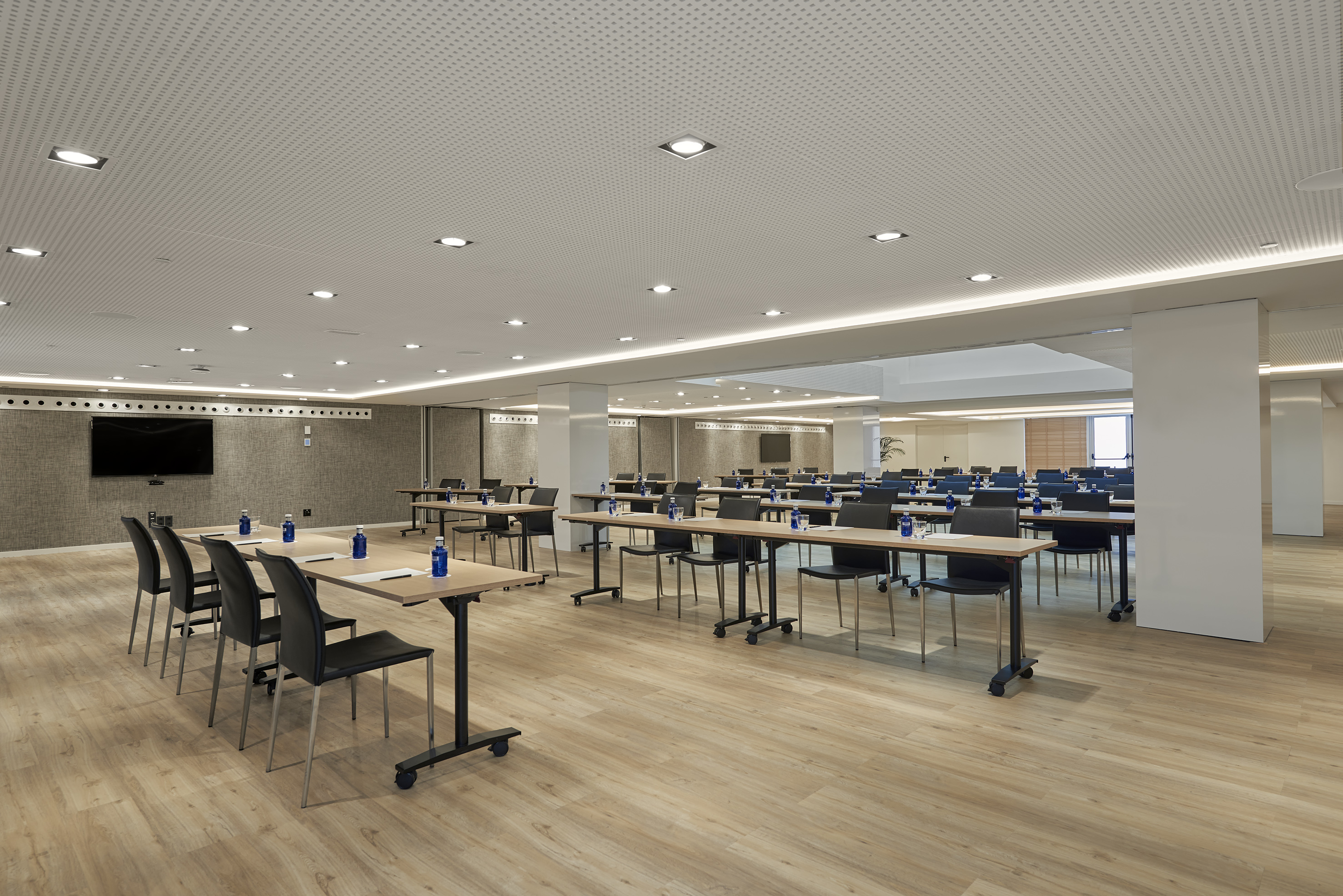 Modern conference room with tables, chairs, and TV for business meetings.