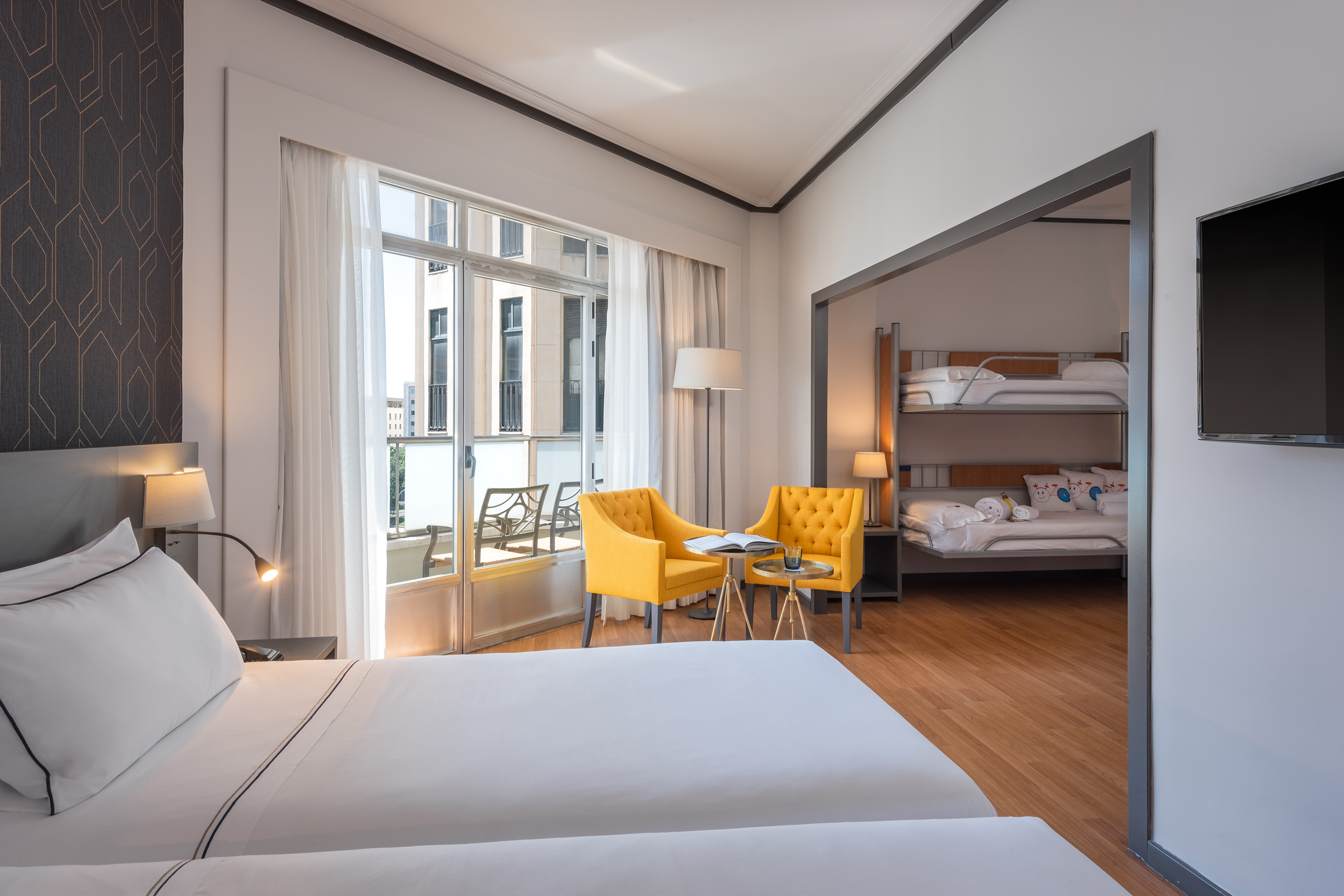 Hotel family room with twin beds, bunk beds, and balcony.