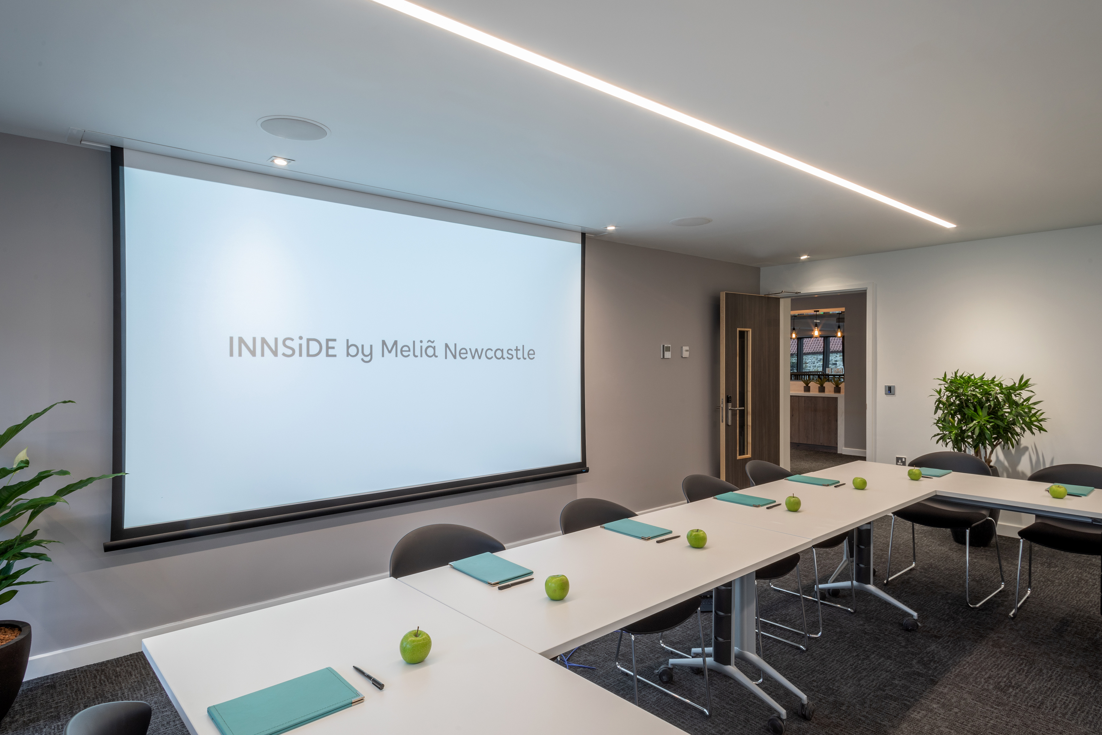 a room with a projector screen and tables