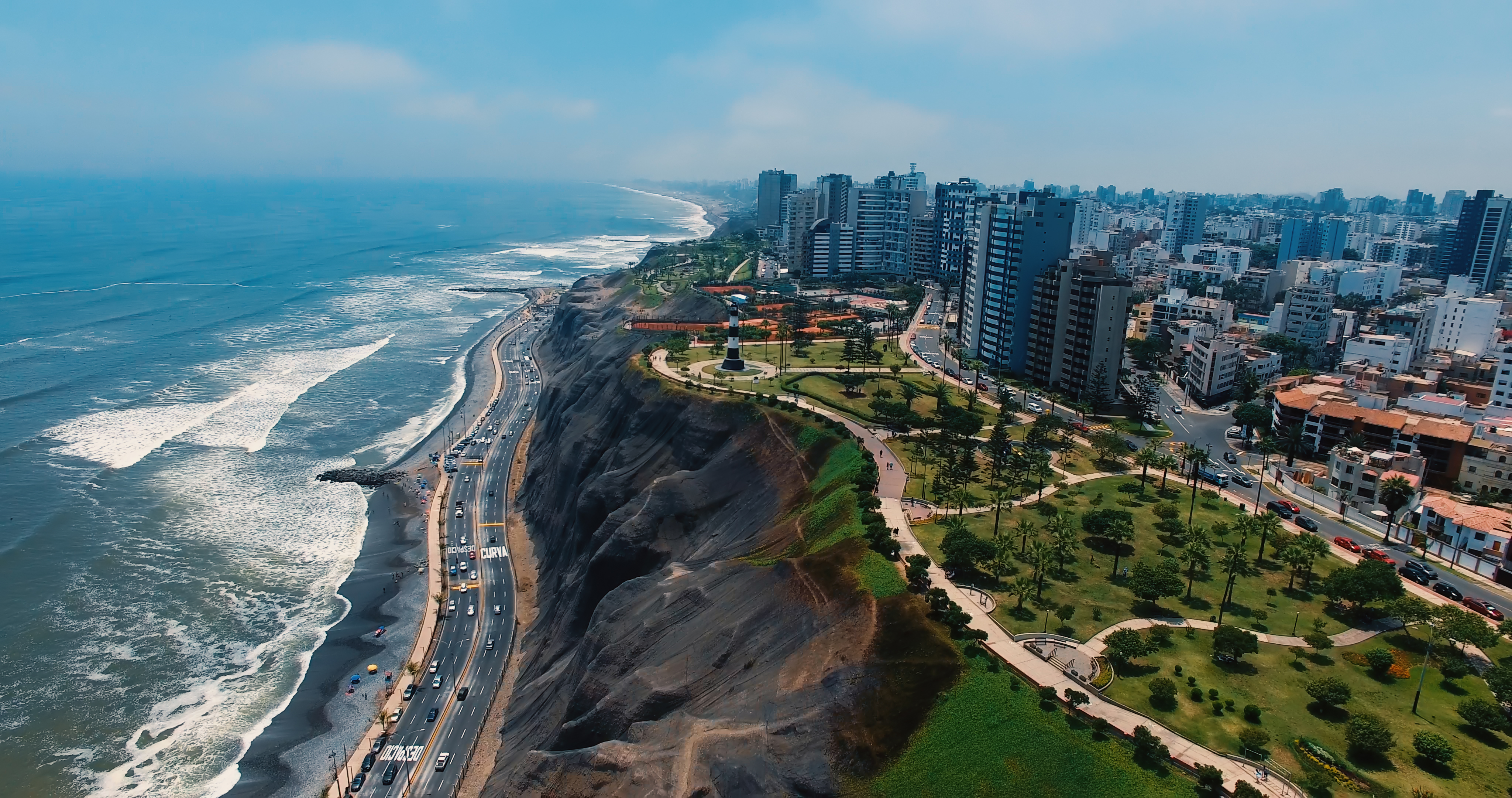 Coastal Lima, Peru: ocean, highway along cliffs, lighthouse, urban skyline.