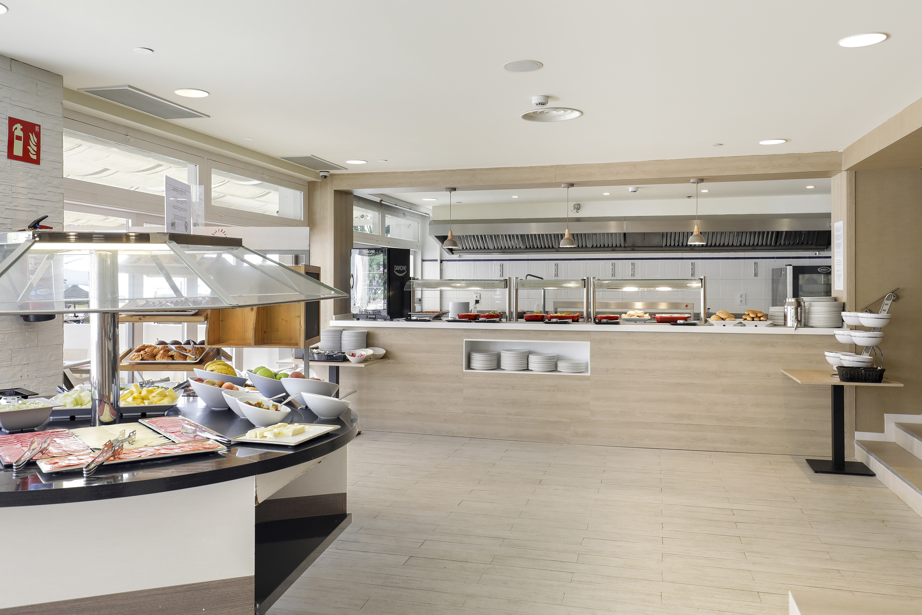 Modern hotel buffet with diverse breakfast selection: cold cuts, fruit, hot food.