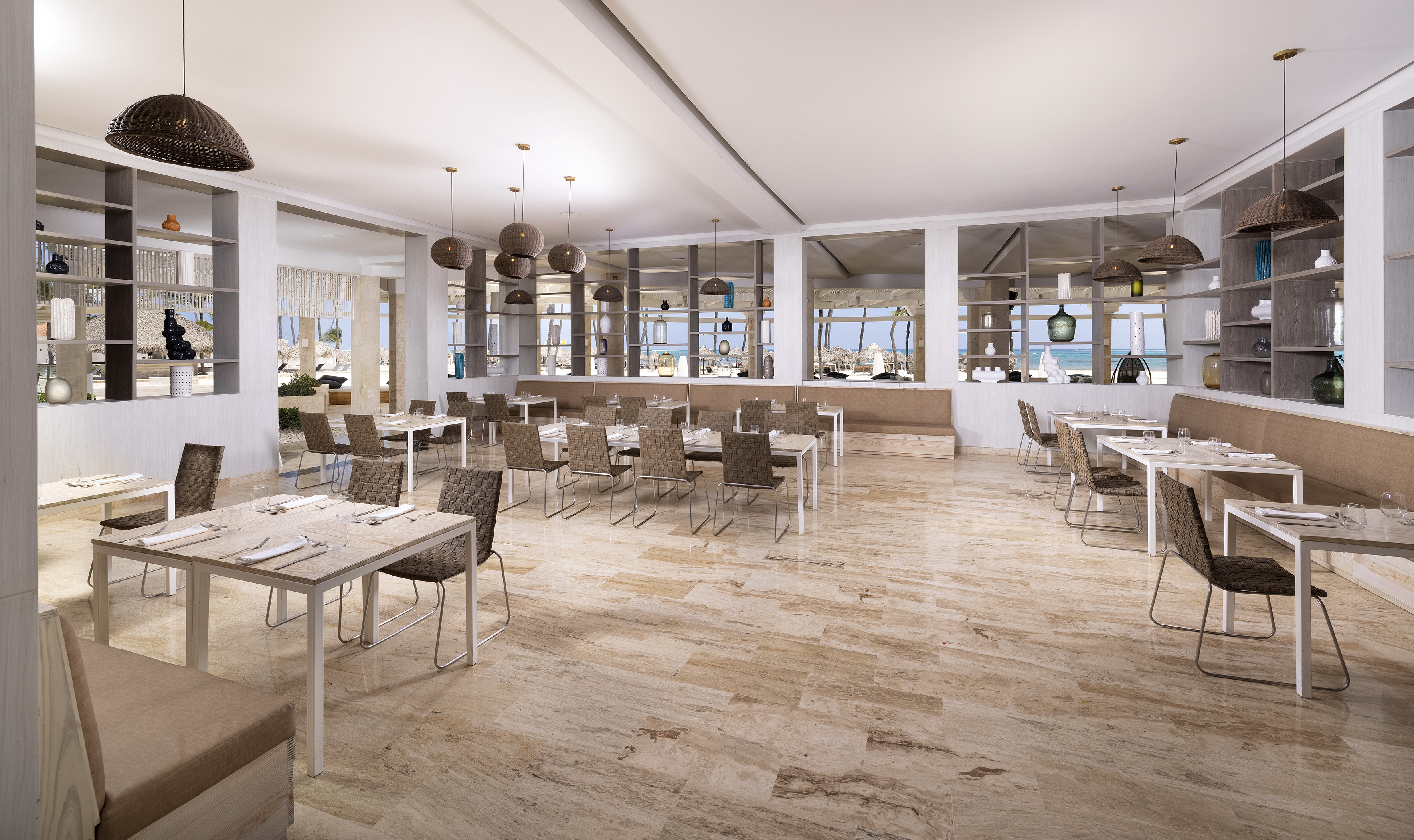 Modern restaurant interior with ocean view, dining tables, and stylish decor.