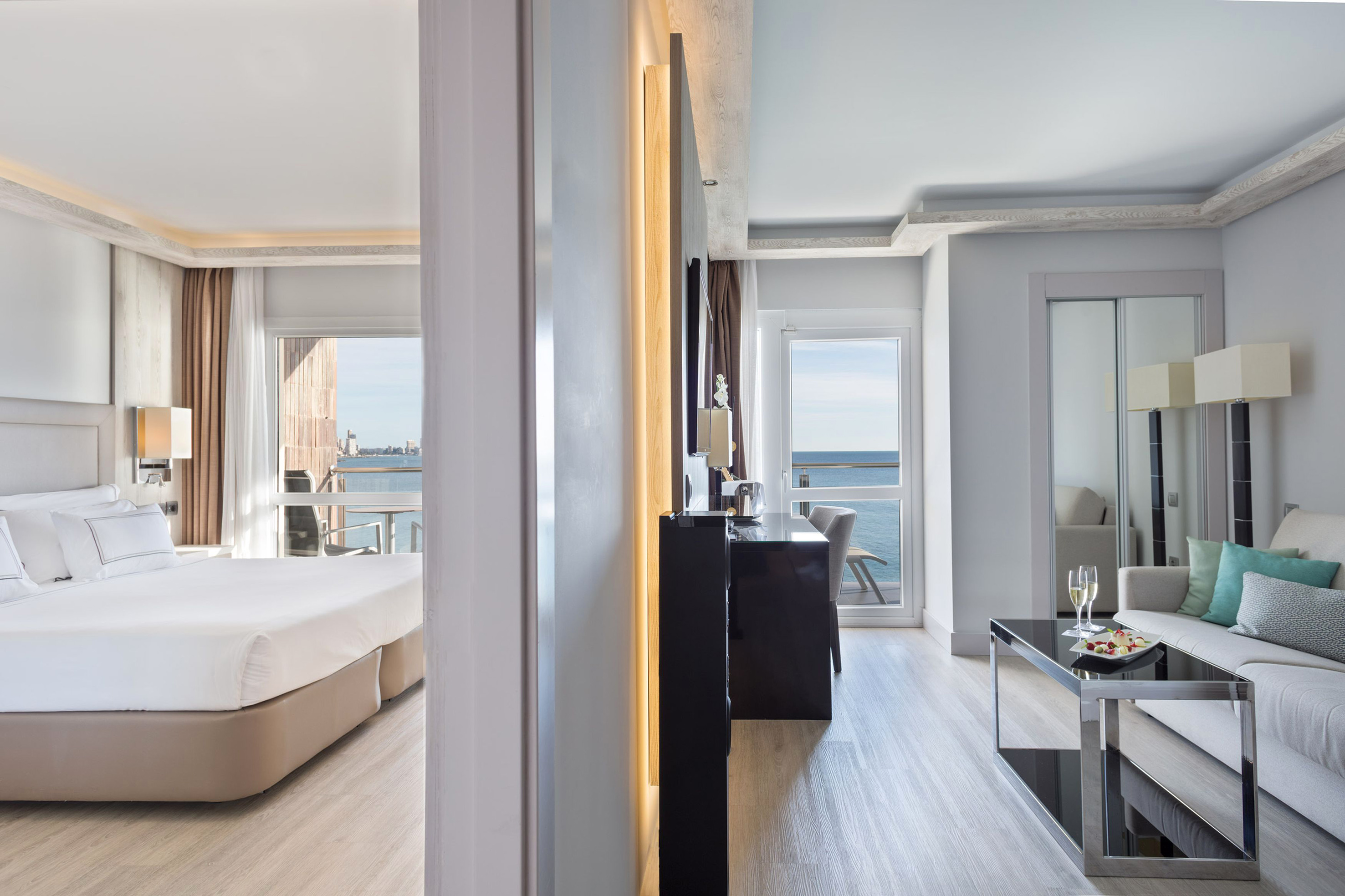 Luxury hotel suite with ocean view, bedroom, and living area.