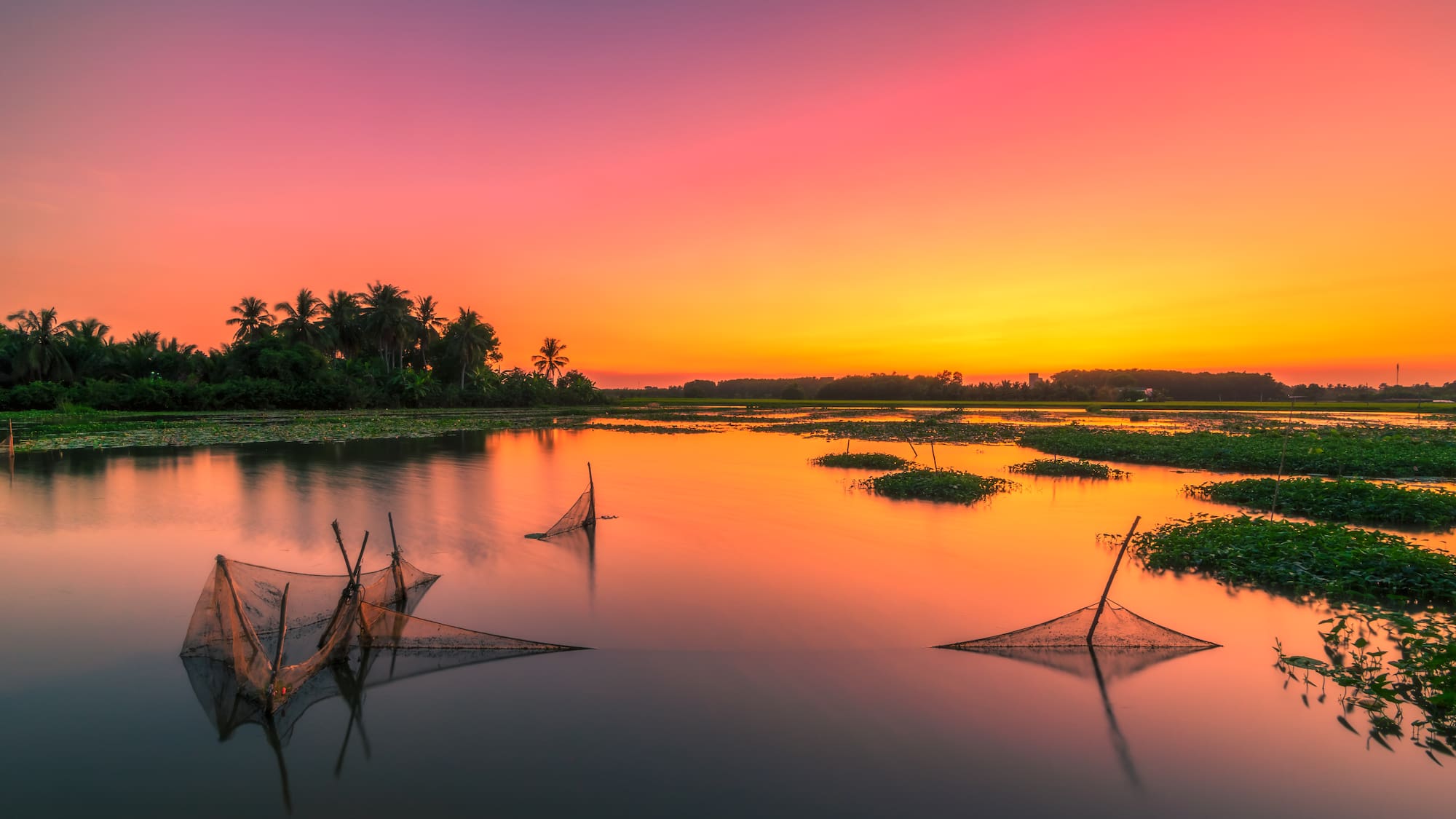 a sunset over a lake with fishing nets