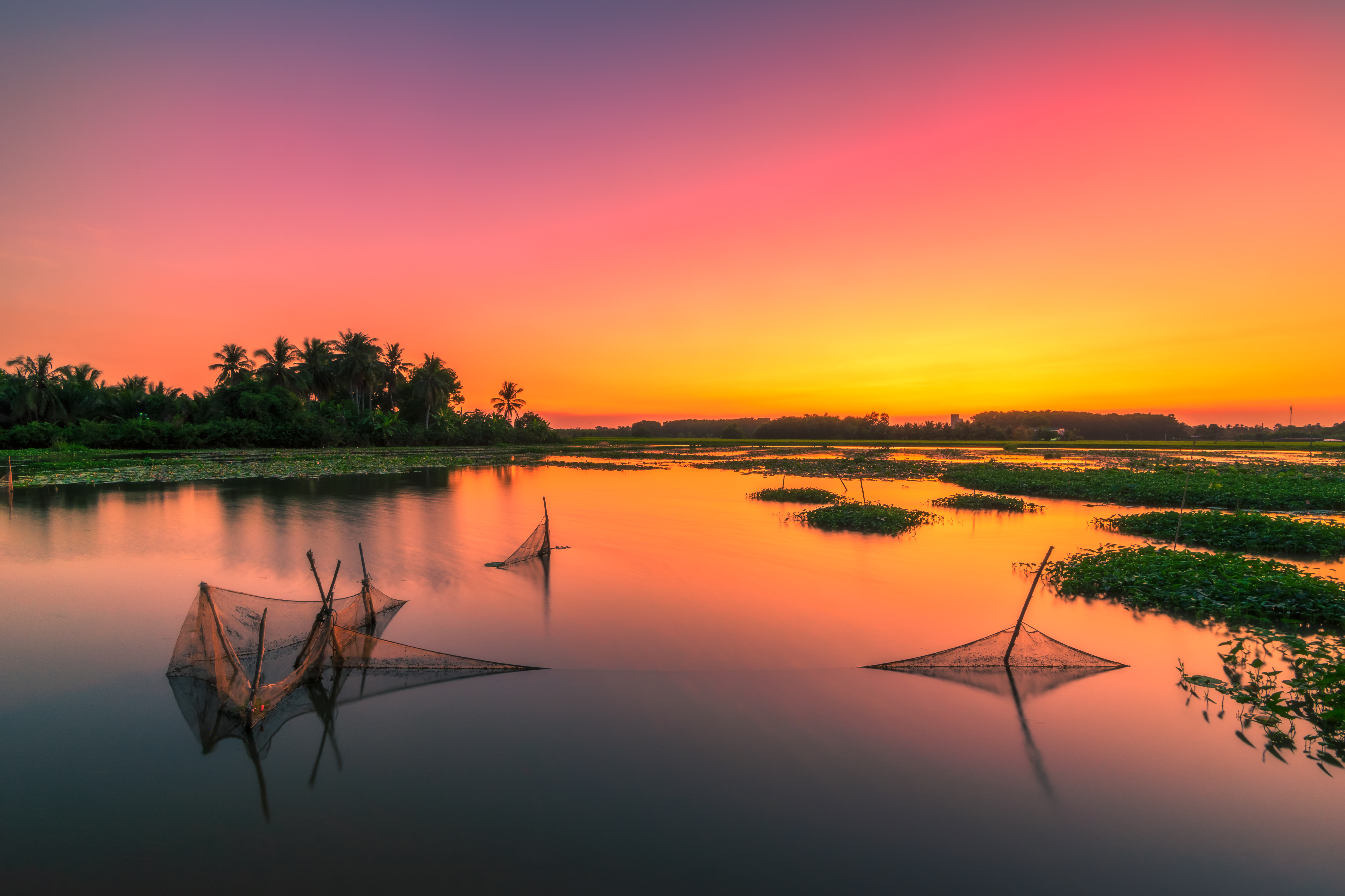 a sunset over a lake with fishing nets