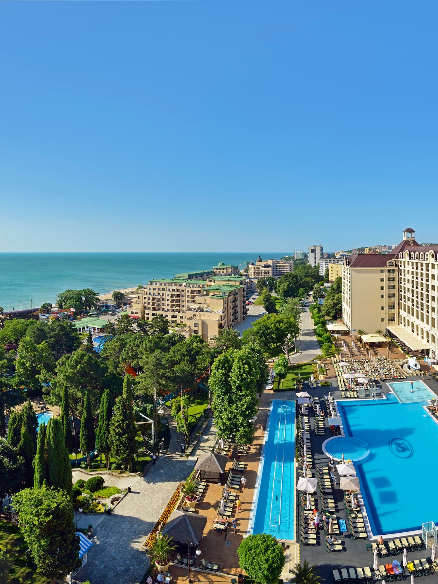 Sprawling beachfront resort with pools, large hotel buildings, and clear blue sea.
