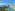 Beachfront resort with large hotel buildings, blue pools, lush gardens, and sea.