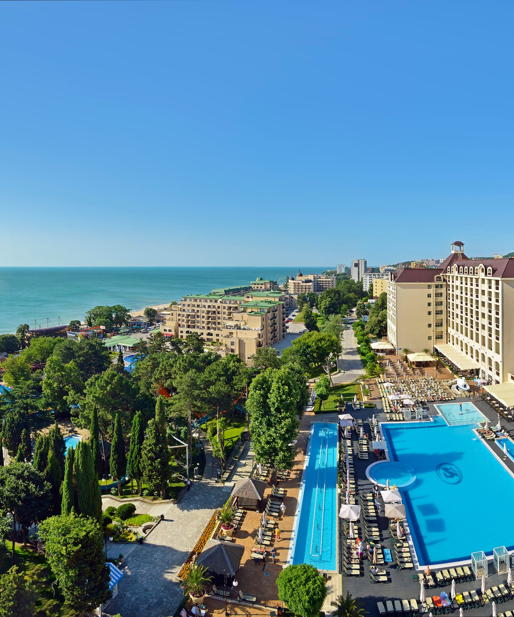 Sprawling beachfront resort with pools, large hotel buildings, and clear blue sea.