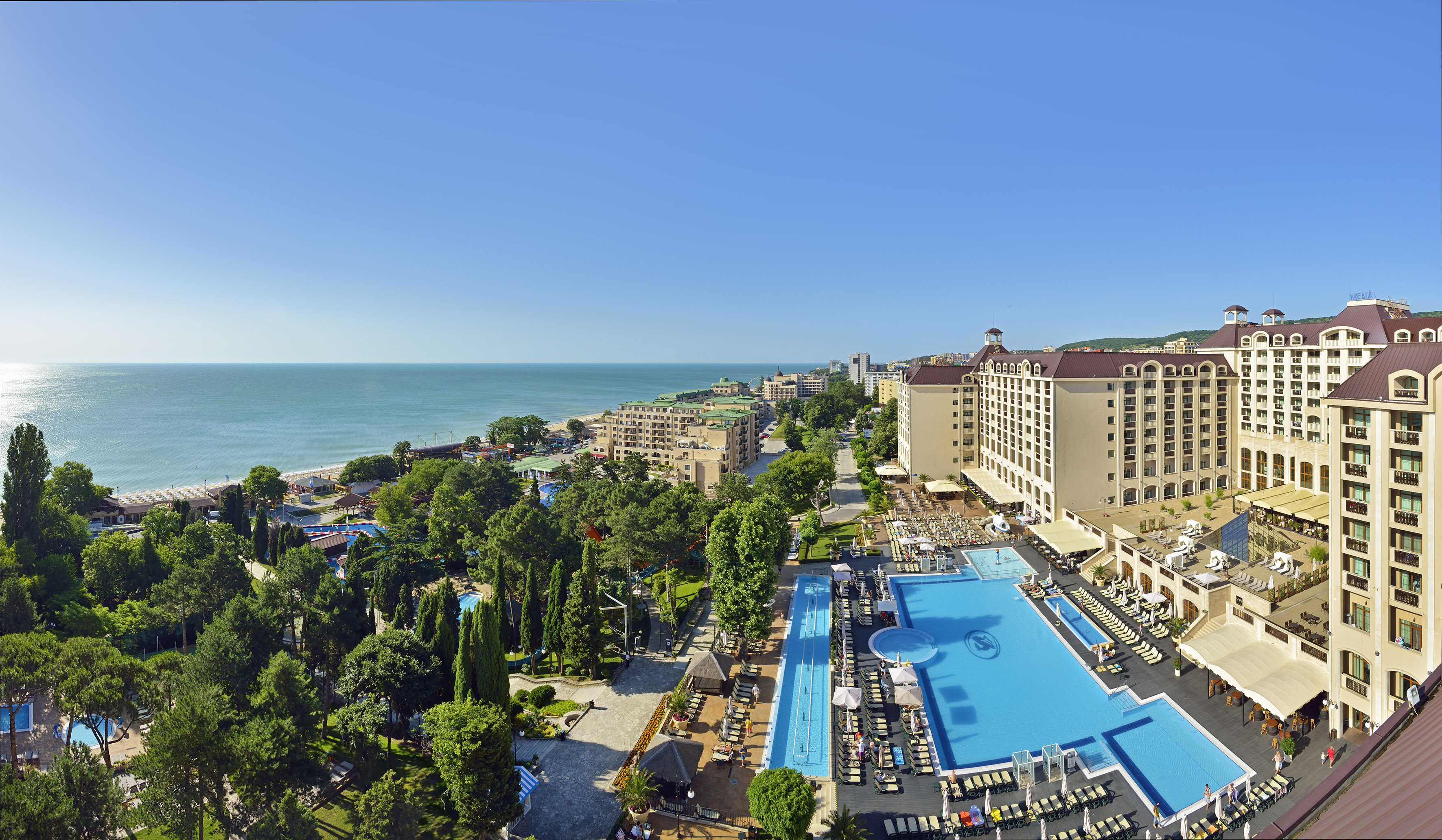 Sprawling beachfront resort with pools, large hotel buildings, and clear blue sea.