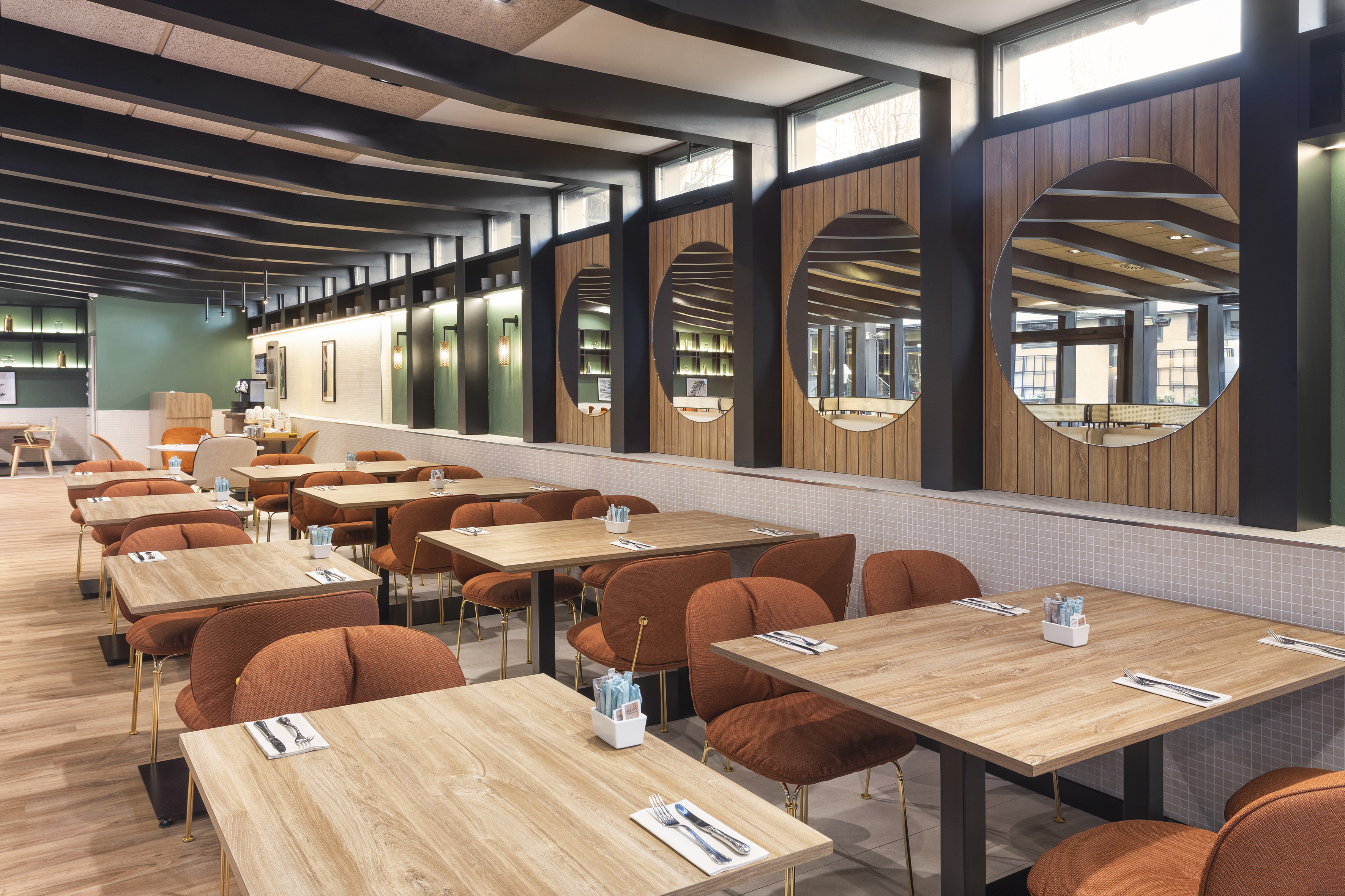 Modern restaurant with wooden tables, orange chairs, and decorative mirrors.