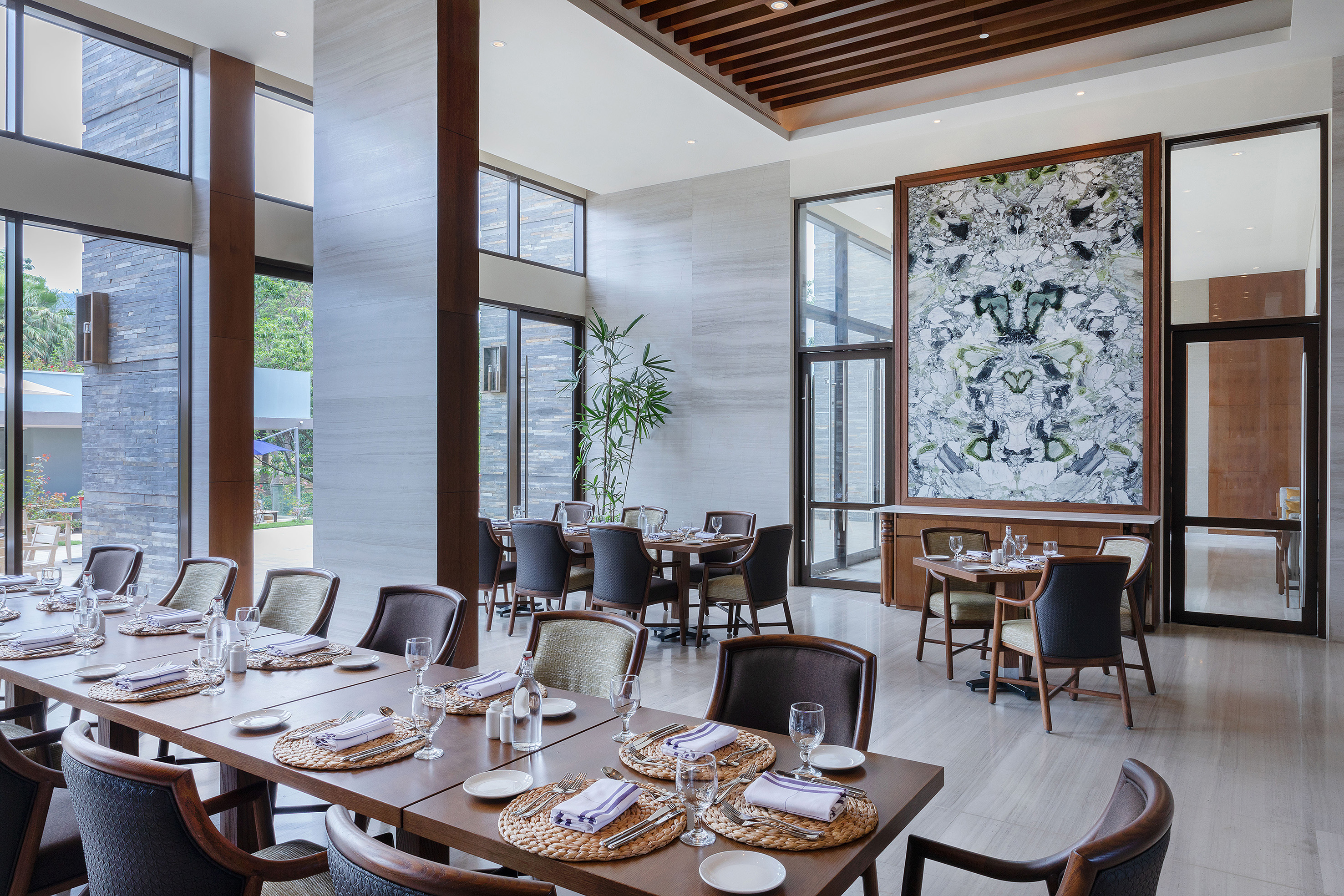 Modern luxury restaurant dining room with elegant set tables, large windows.
