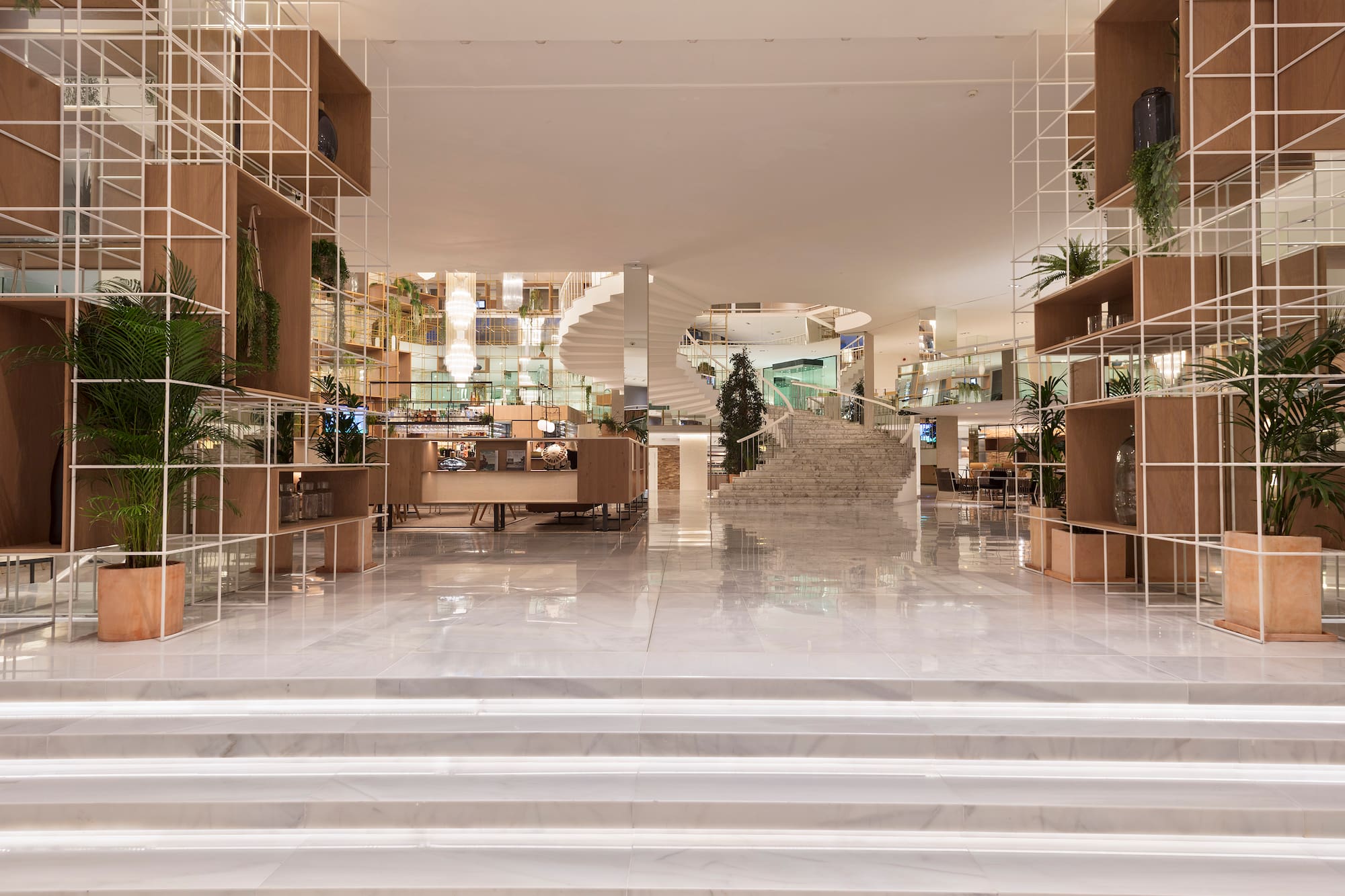 Elegant modern hotel lobby with marble, grid shelving, and spiral staircase.