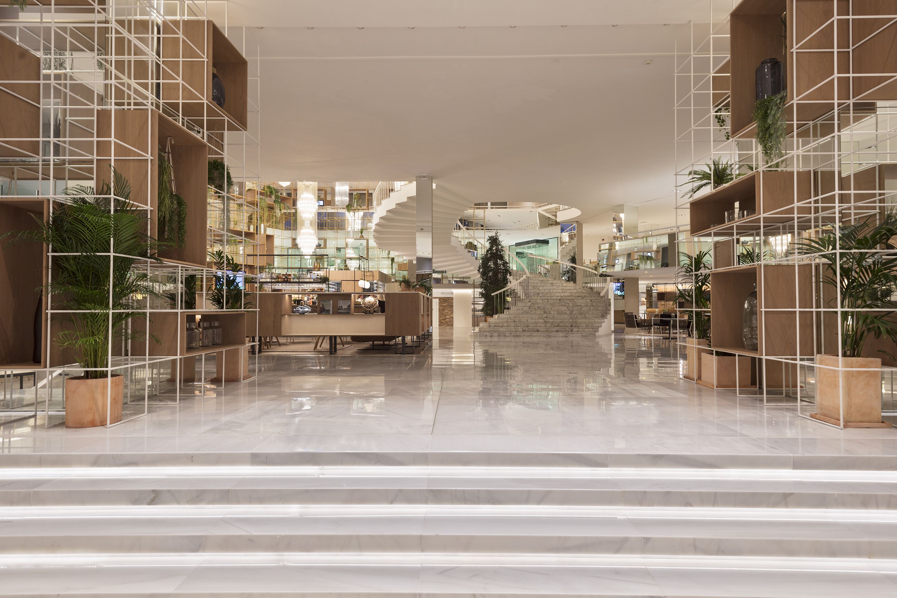 Elegant modern hotel lobby with marble, grid shelving, and spiral staircase.