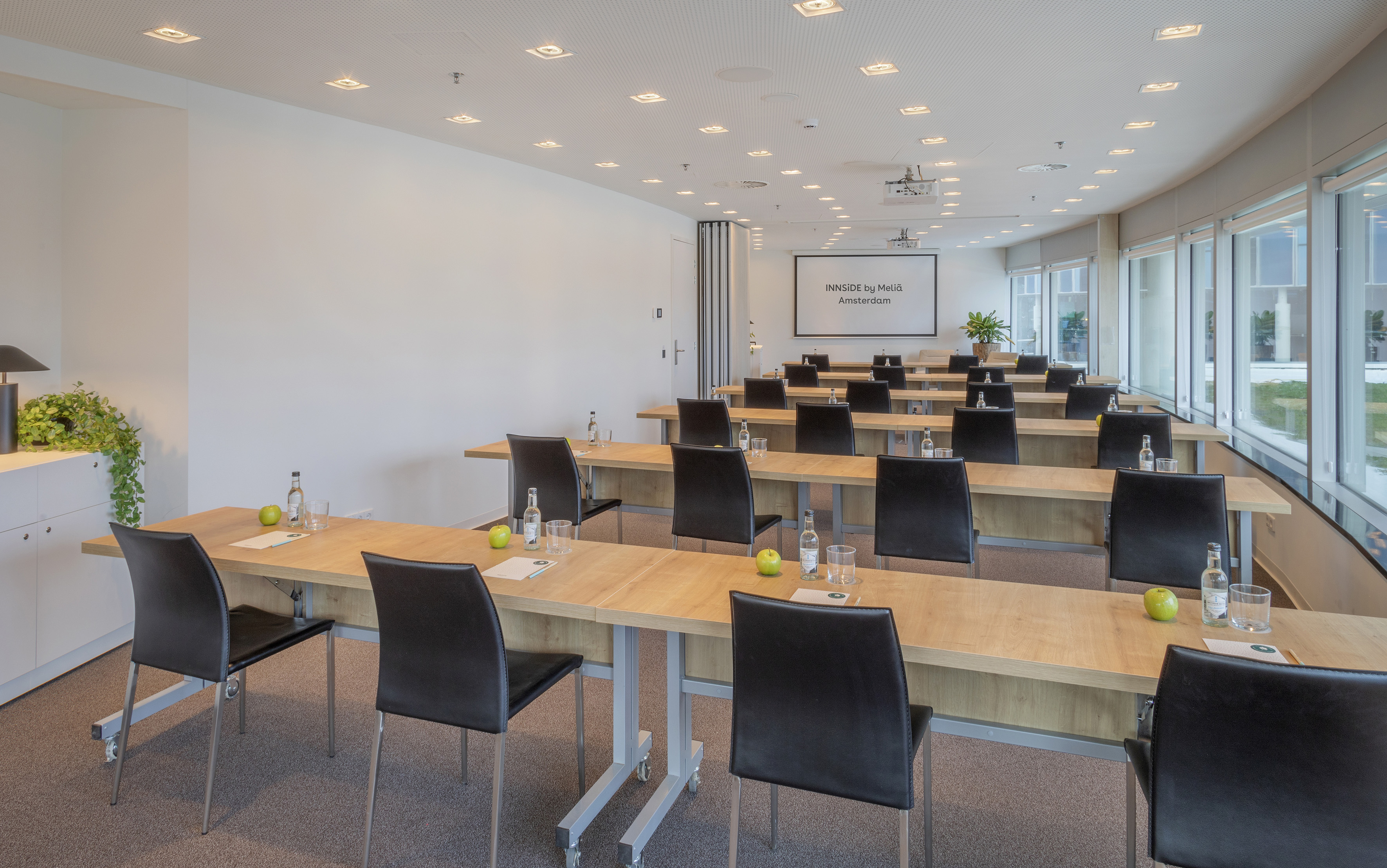 INNSIDE by Meliá Amsterdam conference room with tables, chairs, and projector.