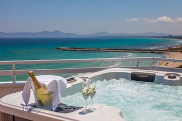 a hot tub with a bottle of champagne and two glasses of wine on a balcony overlooking the ocean