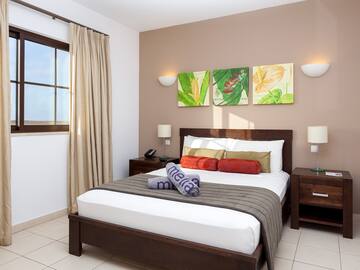 a bed with a brown blanket and pillows in a room with a window