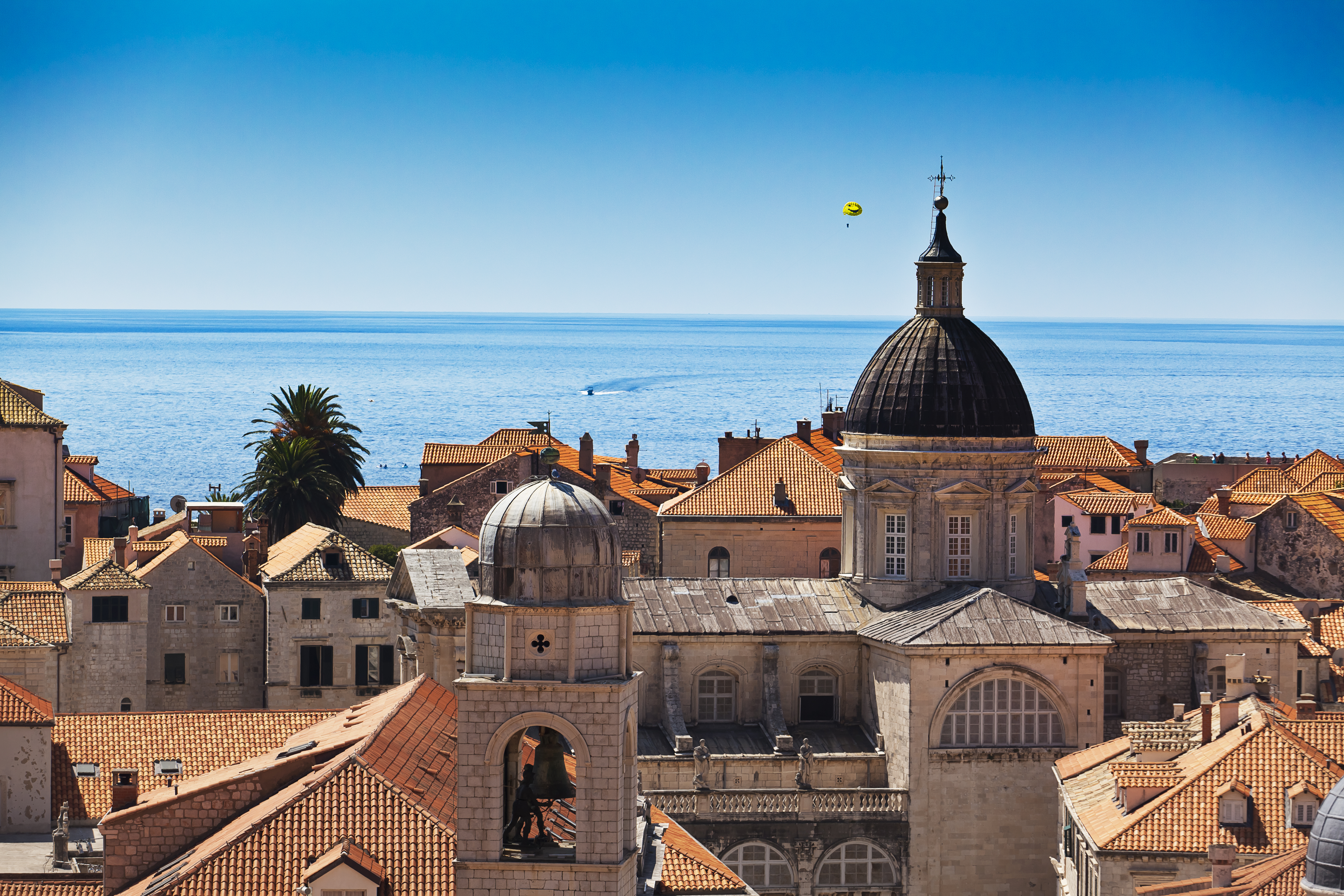 a rooftops of a town with a bell tower and a large body of water