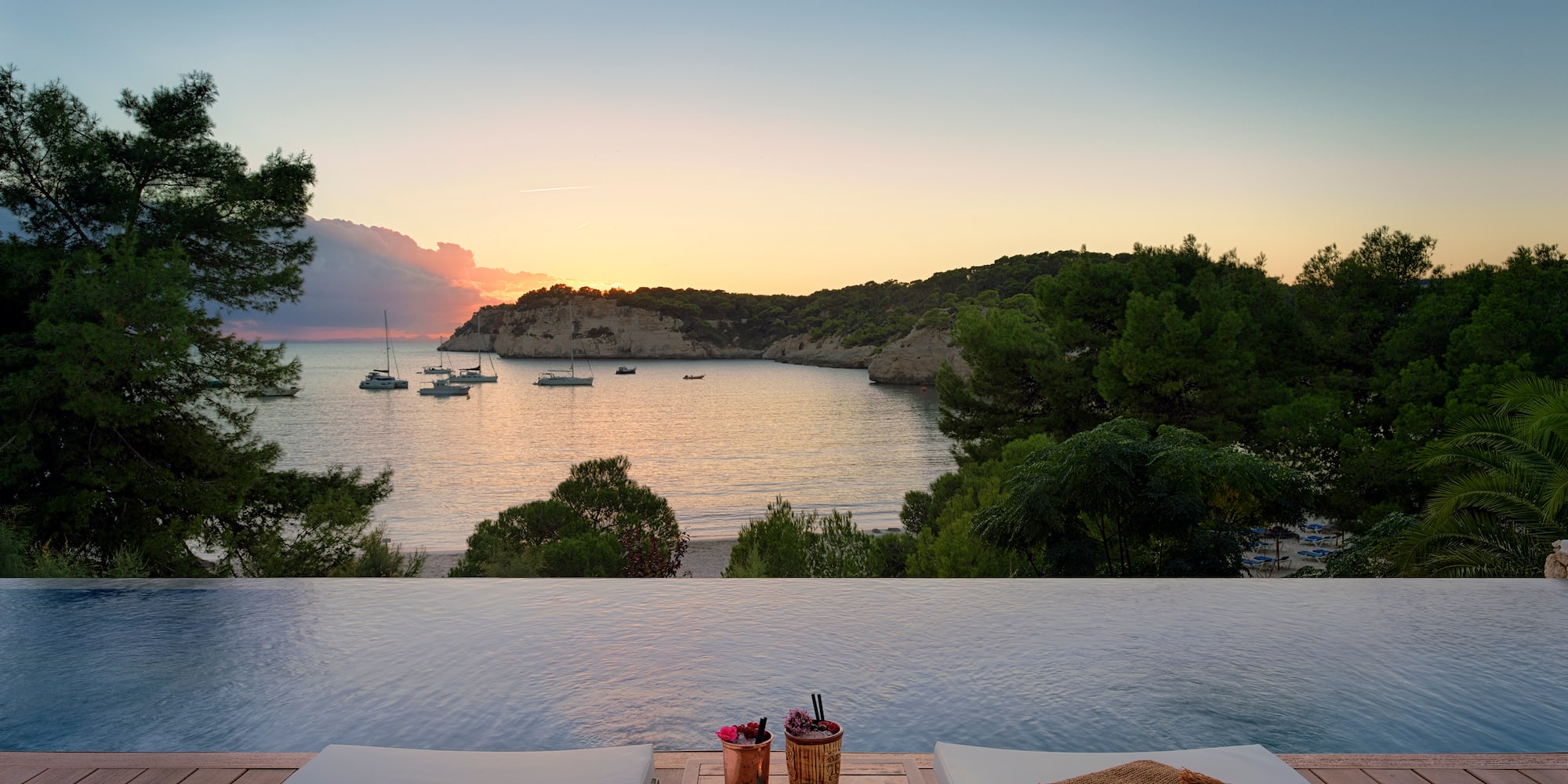 a pool with a view of the ocean and boats in the background