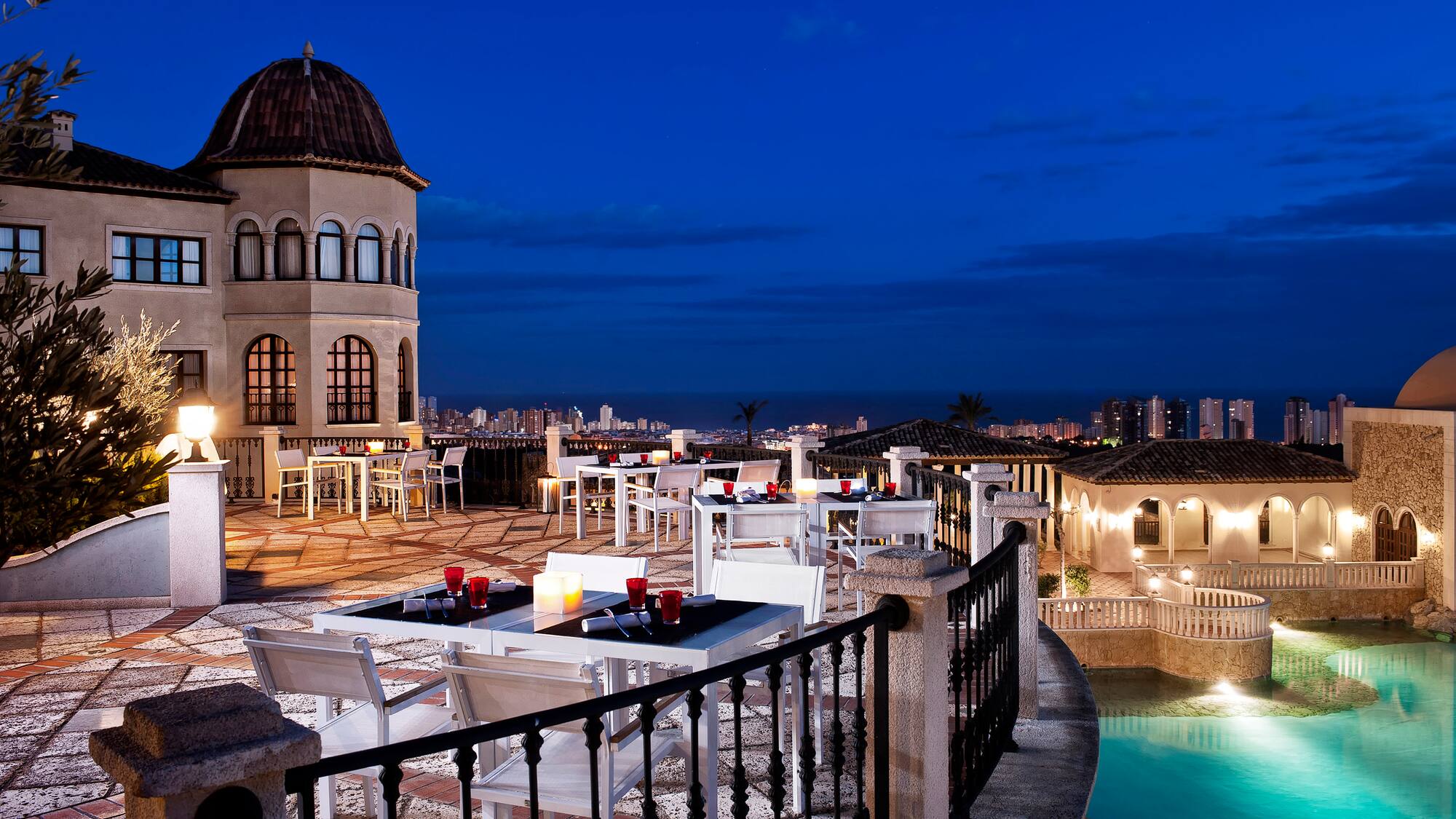a rooftop patio with a pool and tables and chairs