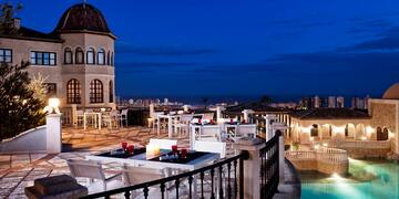 a rooftop patio with a pool and tables and chairs