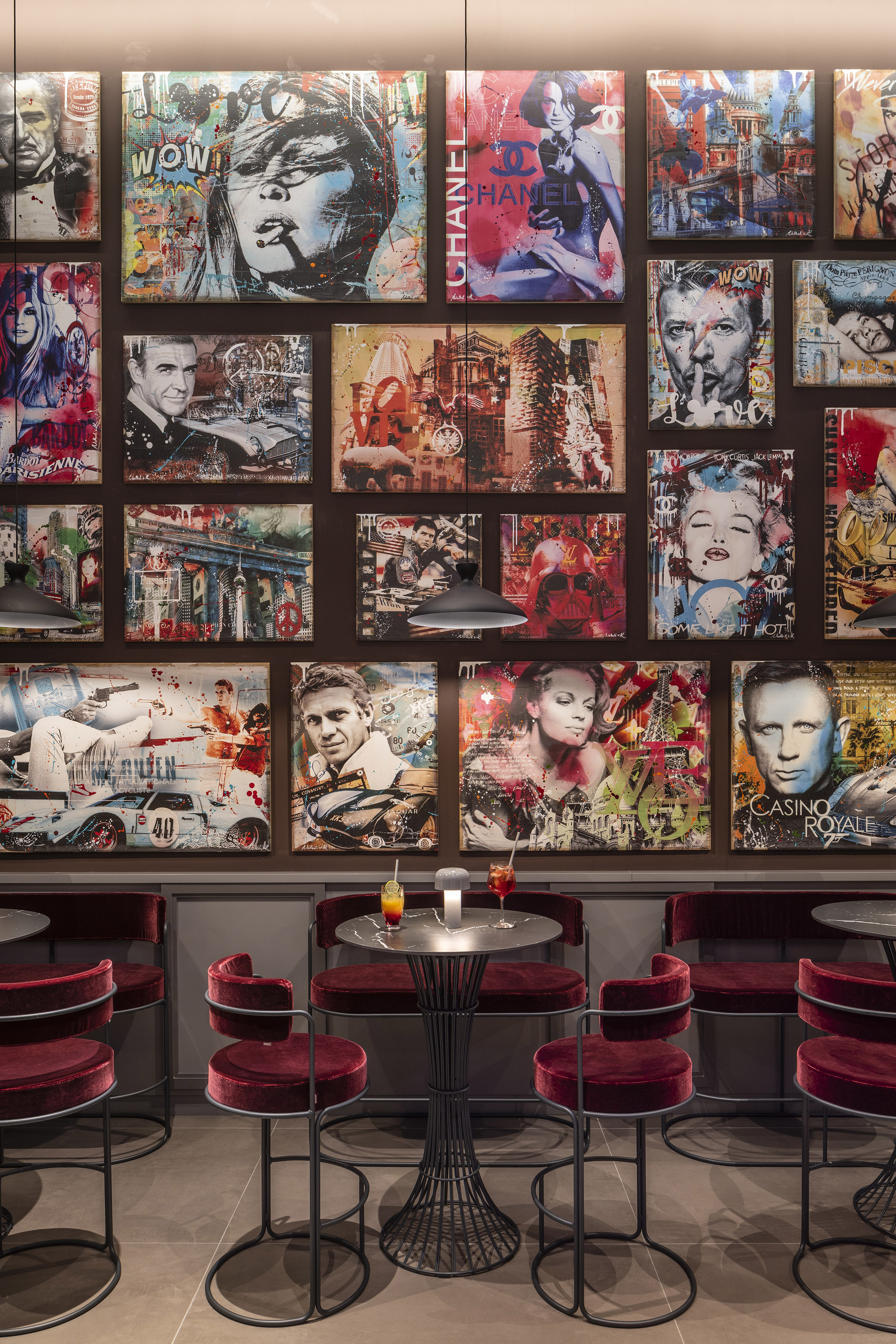 Vibrant bar lounge featuring a large pop art wall with celebrity portraits and red velvet seating.