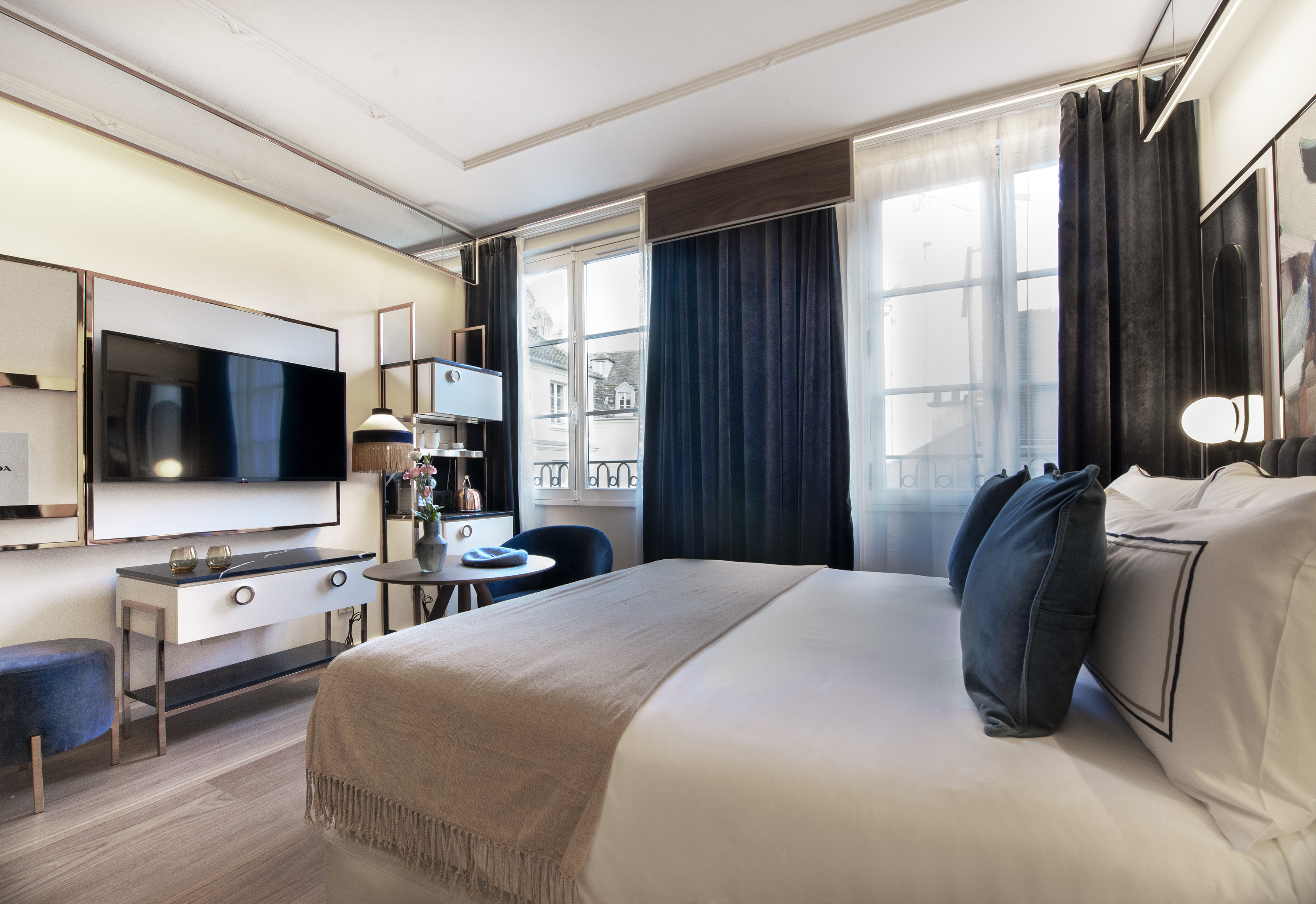 Stylish hotel bedroom with large bed, modern TV, and elegant dark curtains.