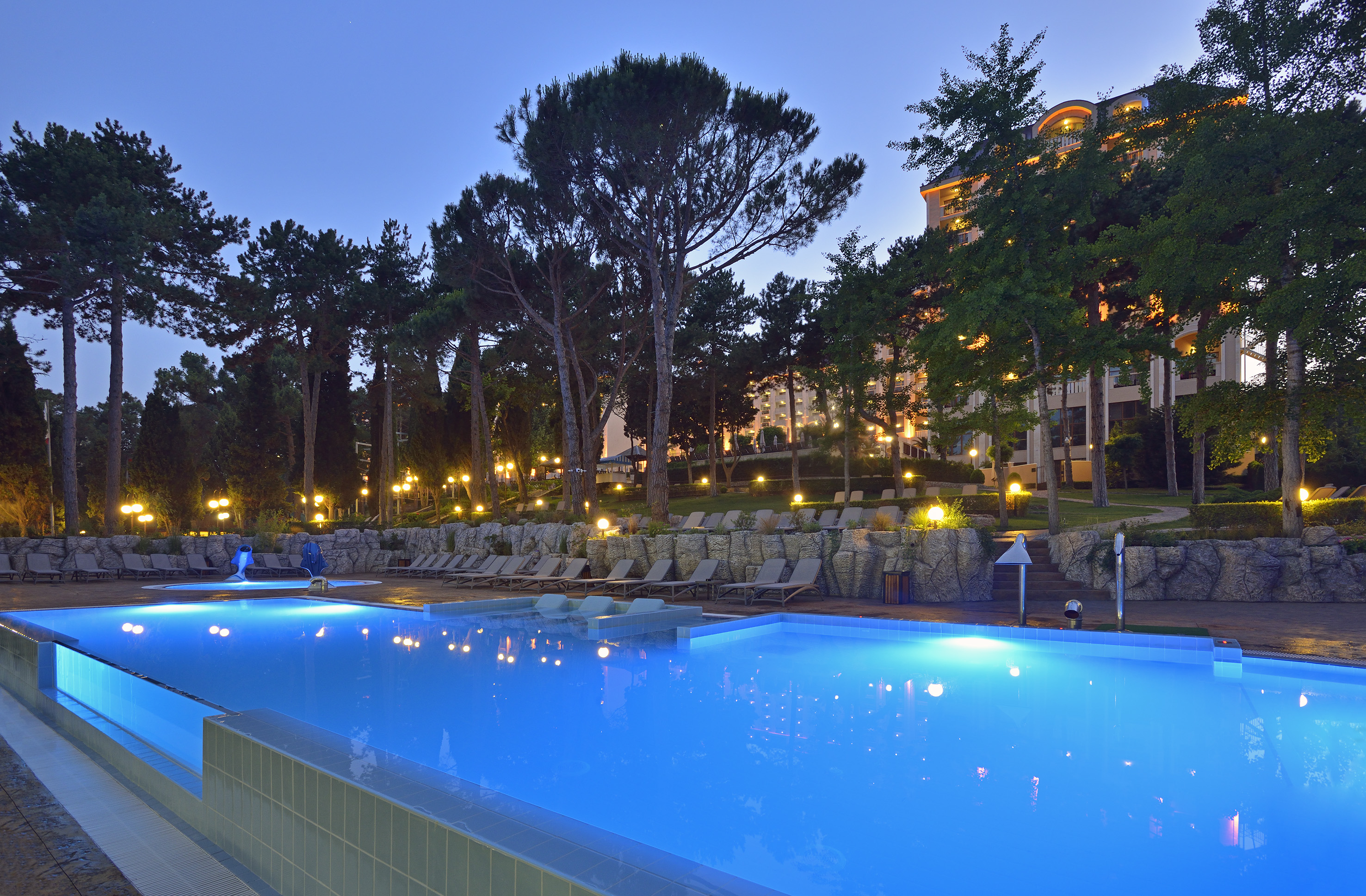 a pool with chairs and trees in the background