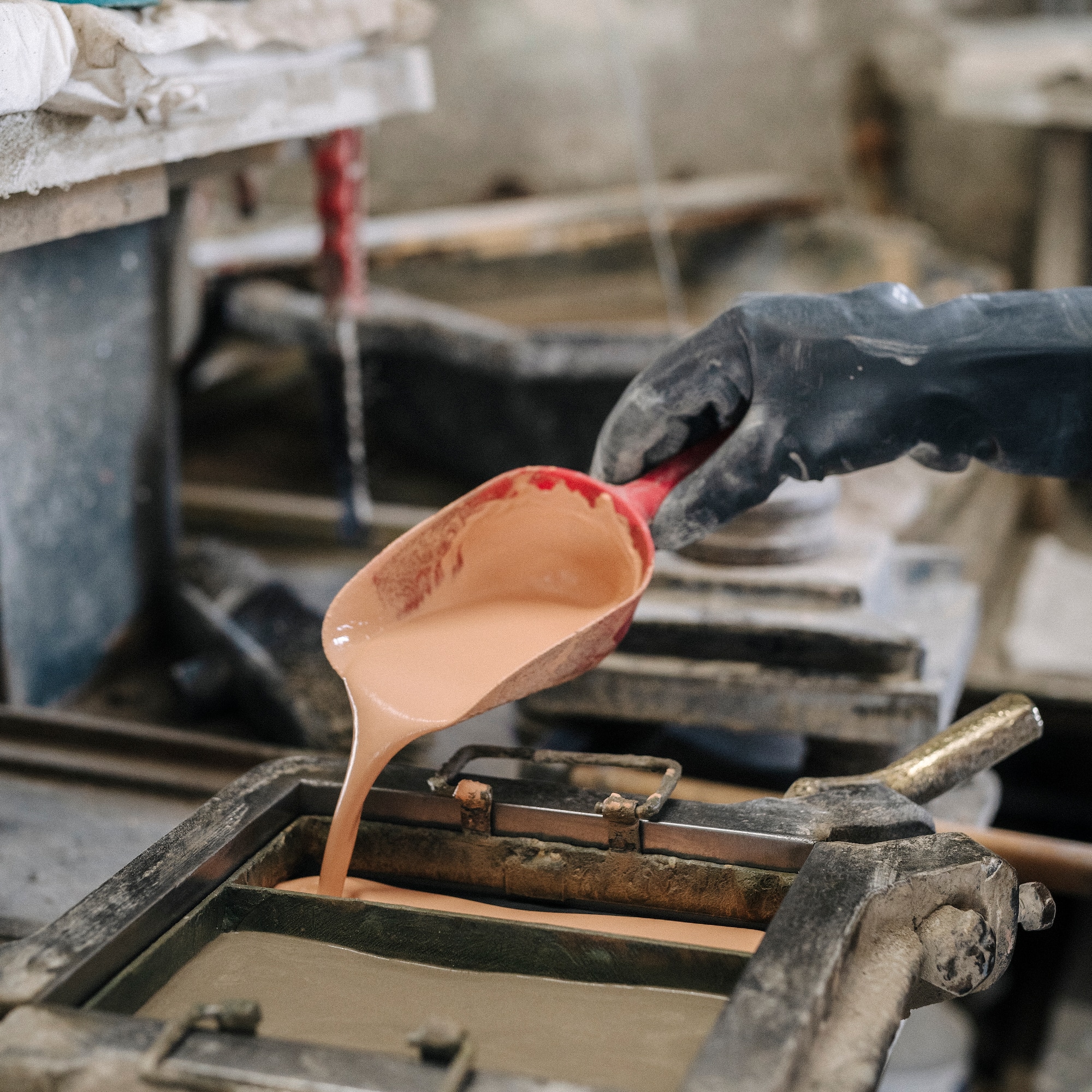 a person pouring liquid into a metal mold