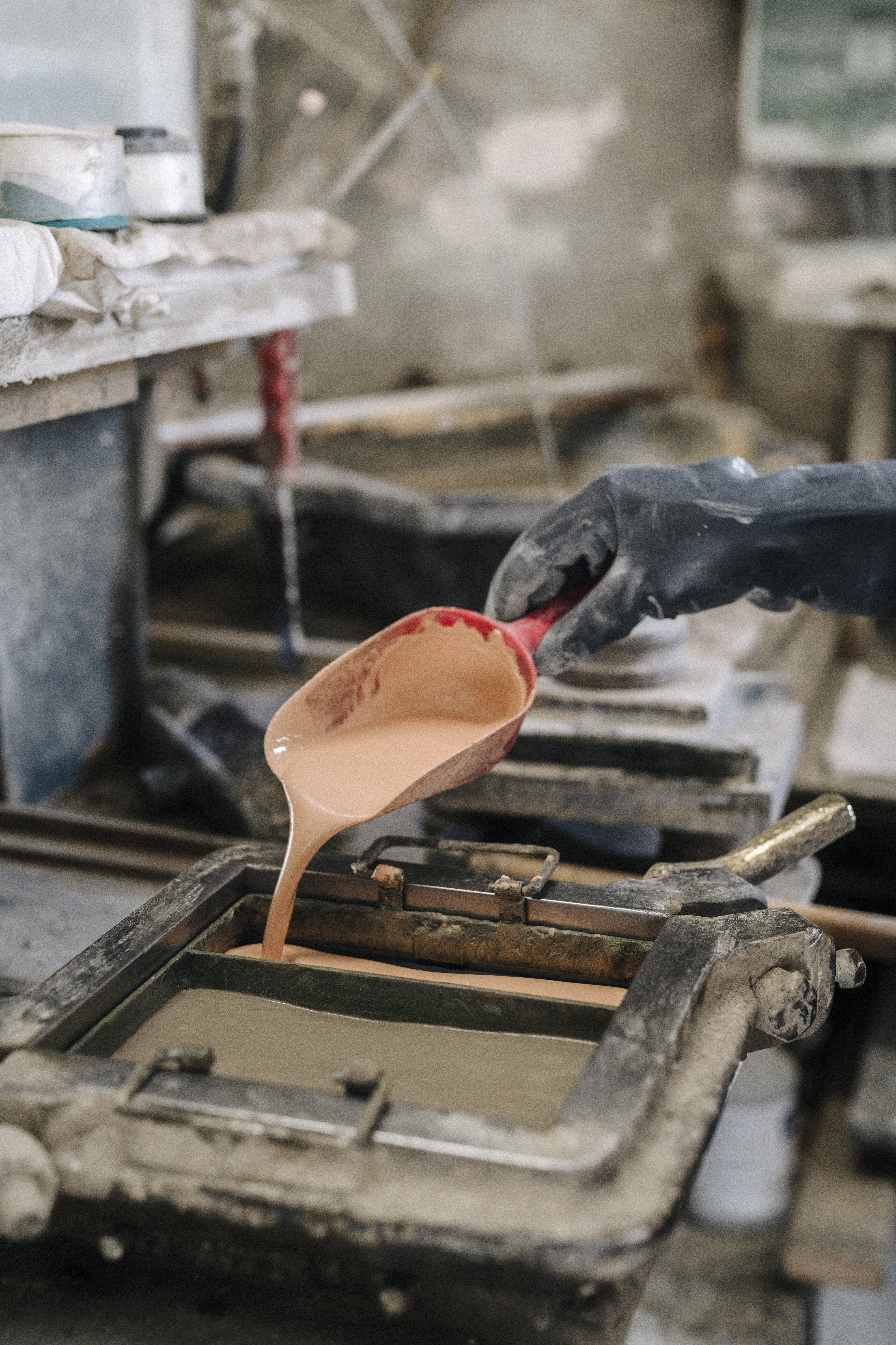 a person pouring liquid into a metal mold