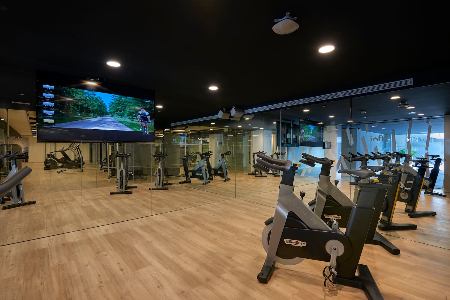 a room with exercise bikes and a large screen