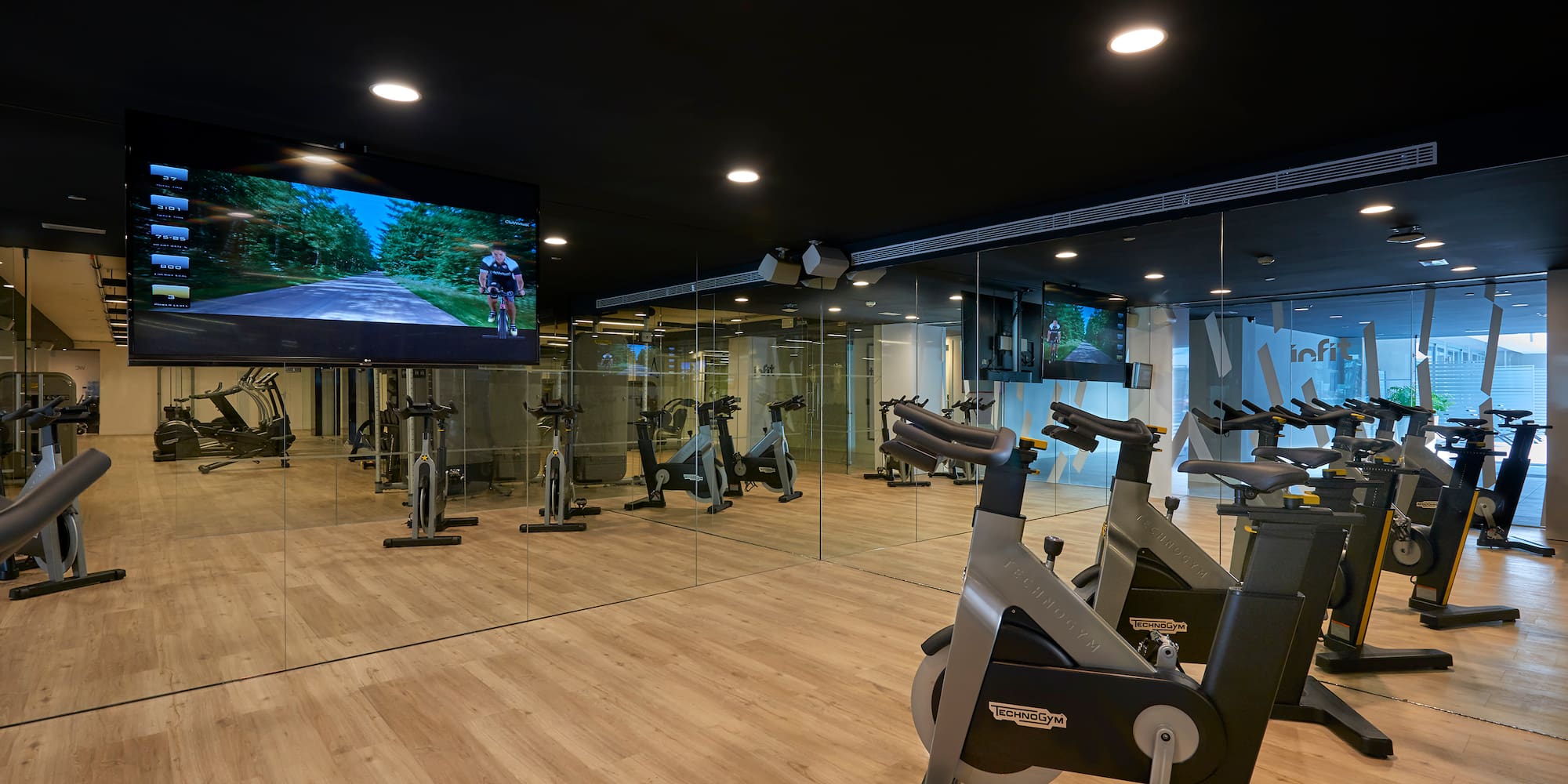 a room with exercise bikes and a large screen