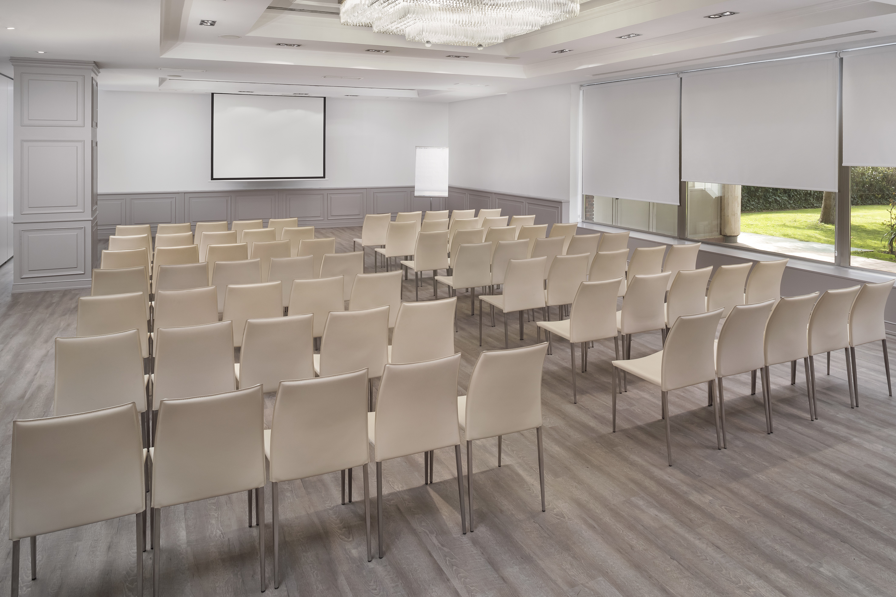 Modern conference room with beige chairs, projection screen, and outdoor view.