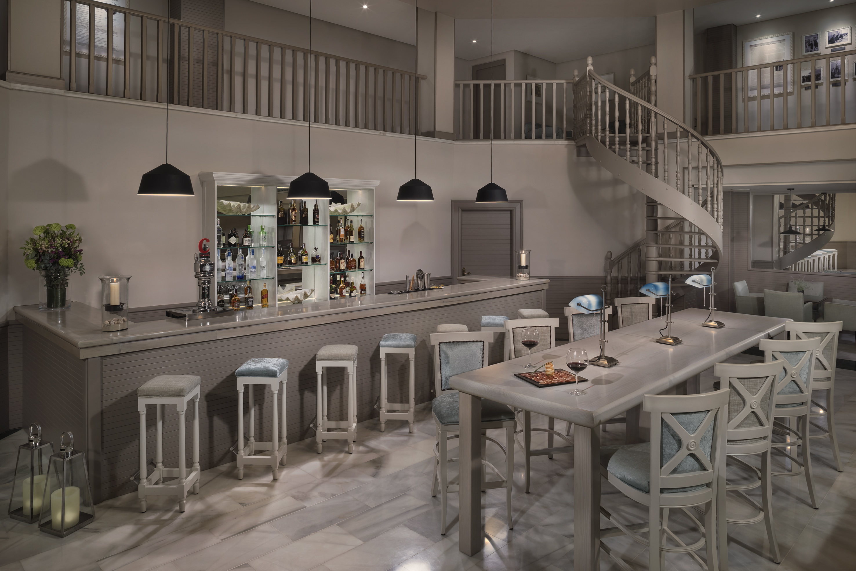 Elegant bar lounge interior with long counter, high table, and spiral staircase.