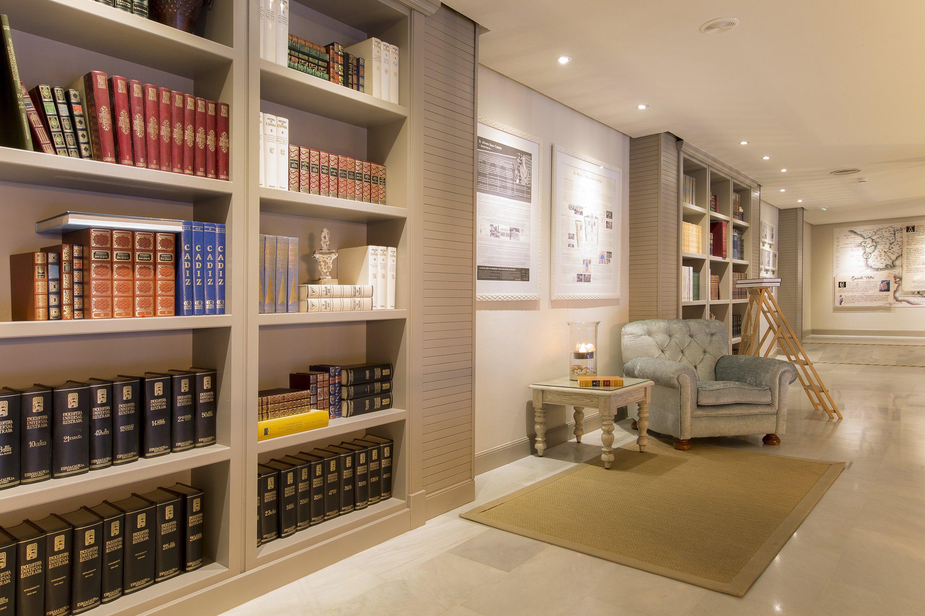 Library with tall bookshelves, cozy tufted armchair, and side table.