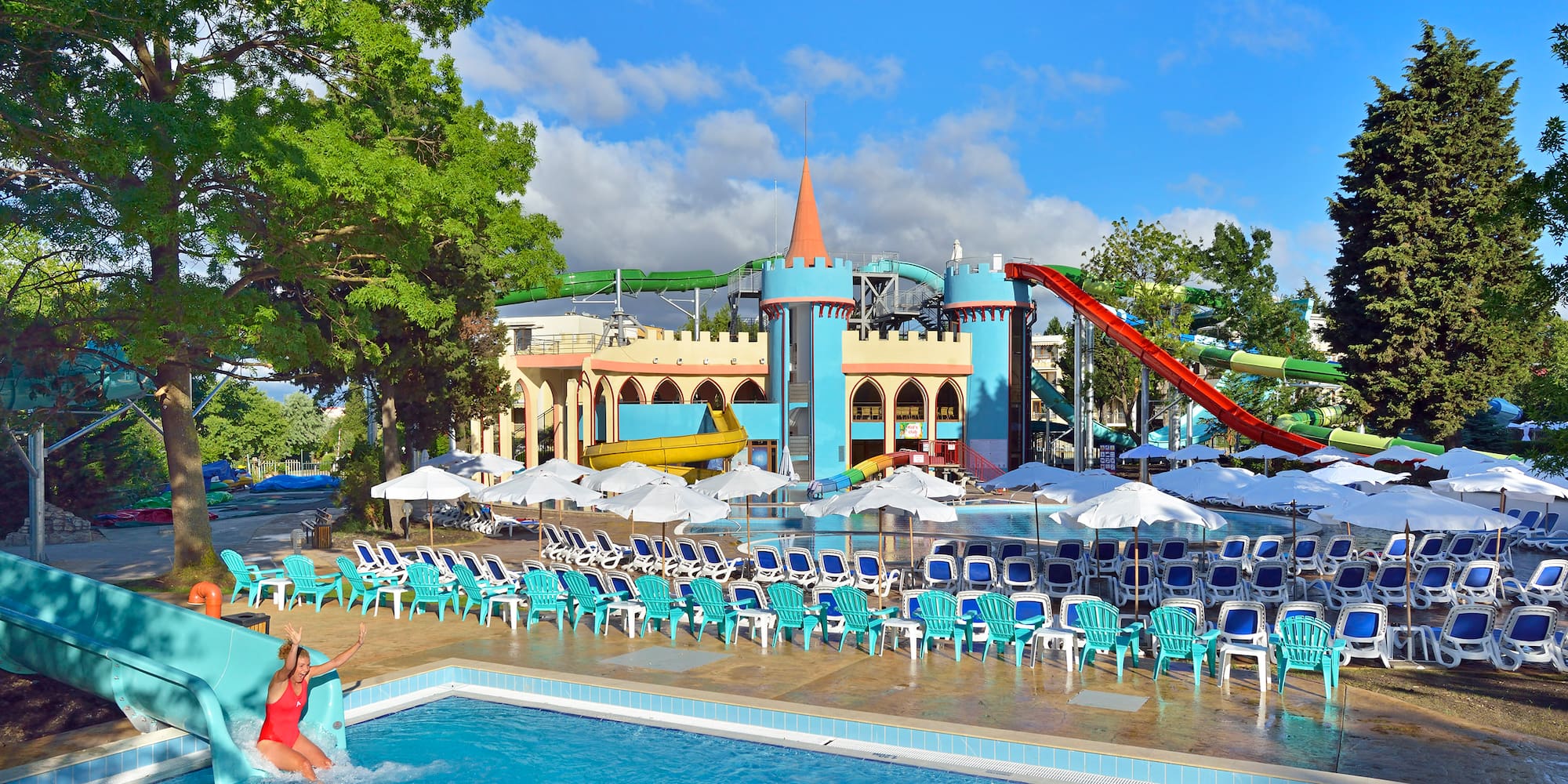a woman in a pool with chairs and a slide
